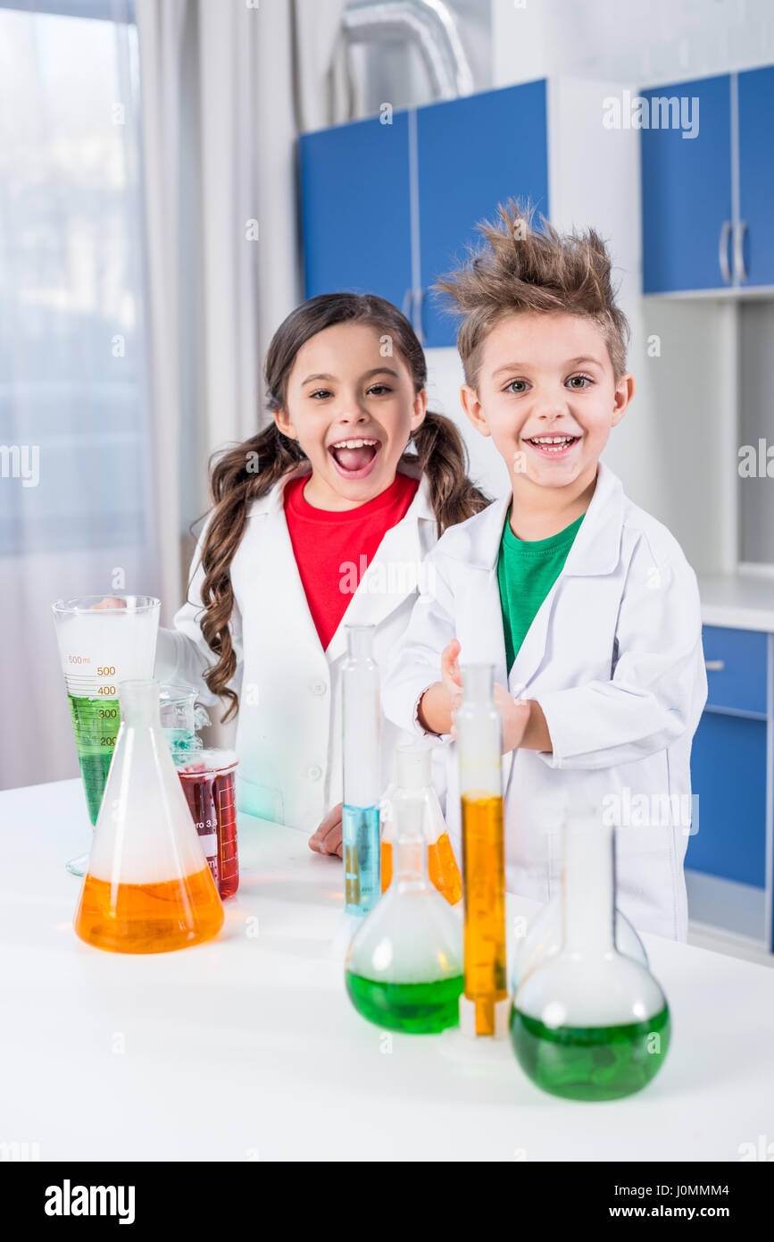 Contenti i bambini in camice da laboratorio in posa di laboratorio chimico e  sorridente in telecamera Foto stock - Alamy
