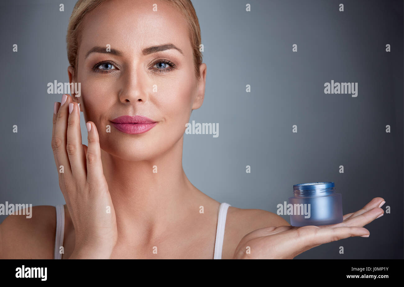 Bella donna nutrito tenendo la crema per la pelle Foto Stock