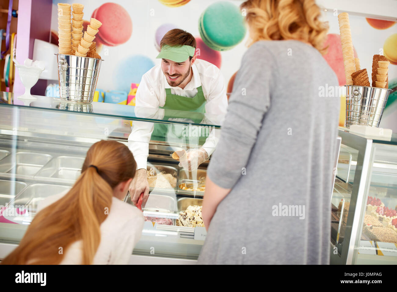 Fornitore maschio in pasticceria serve la ragazza con gelato Foto Stock