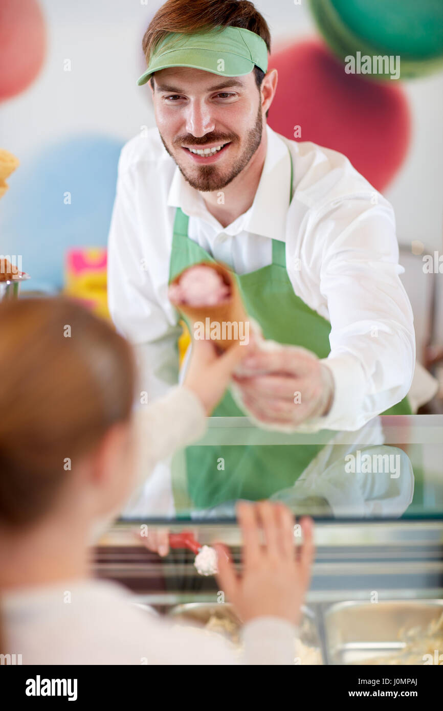 Gentile Venditore maschio nel negozio di caramelle dà gelato alla ragazza Foto Stock