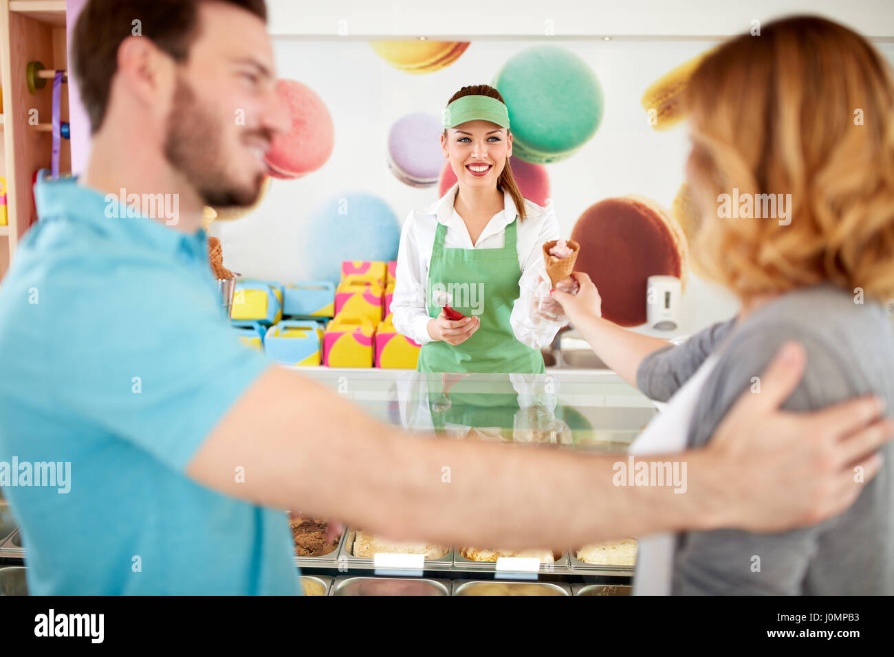Commessa sorridente dà gelato alla donna nel panificio negozio Foto Stock