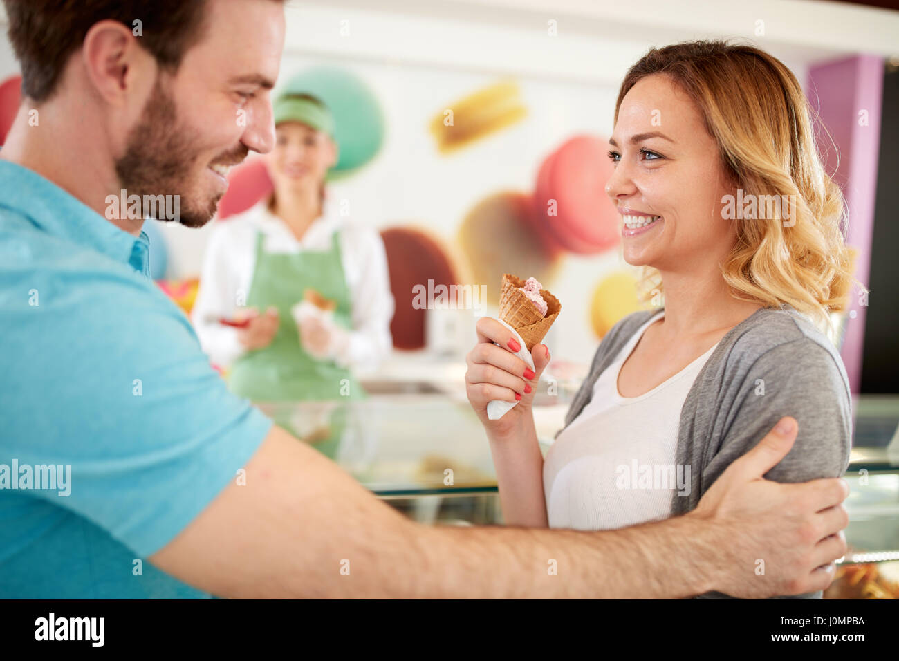 Donna felice godere di gelati in pasticceria con affascinante uomo Foto Stock