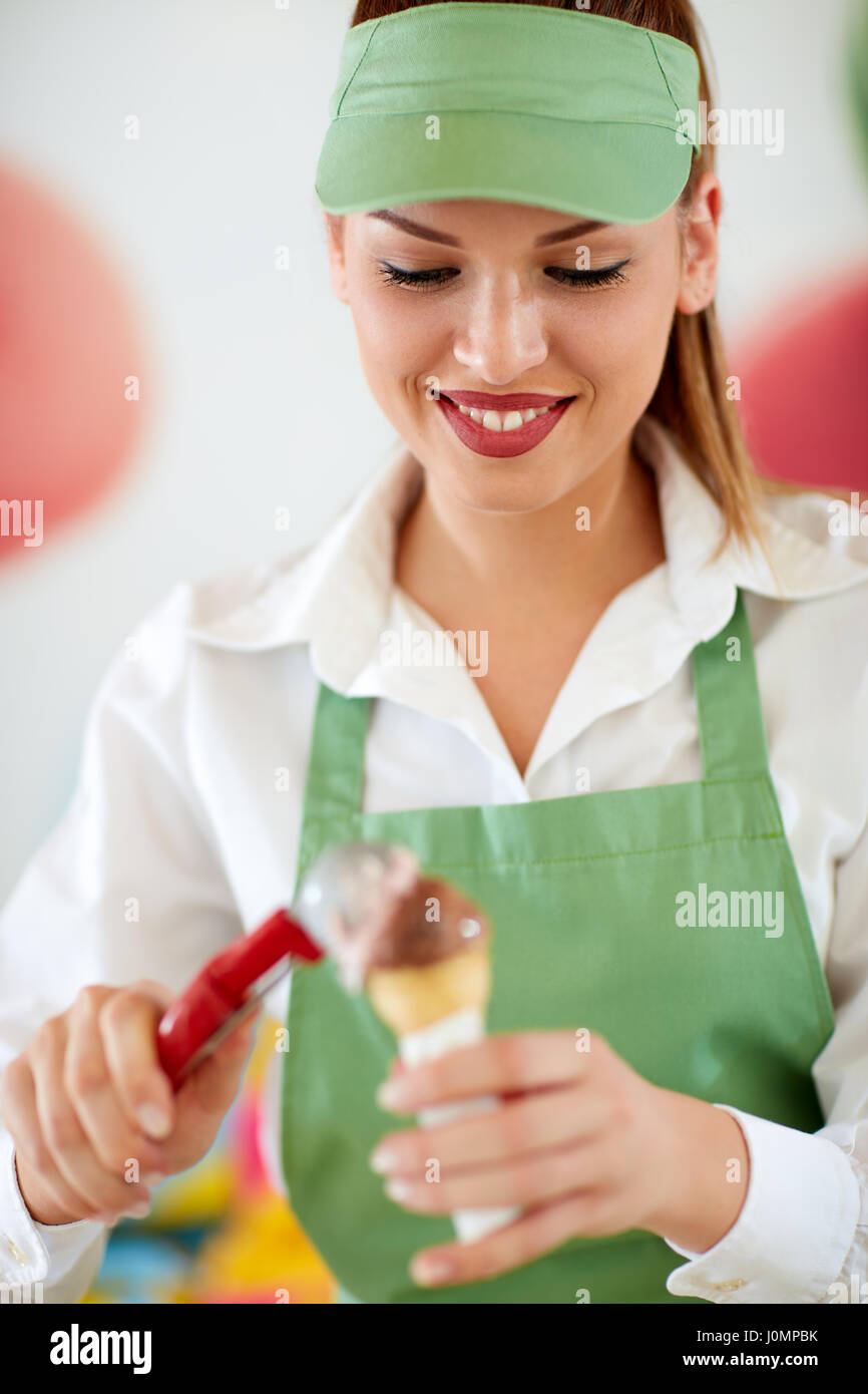 Fornitore femmina in pasticceria mettendo il gelato al cioccolato palla in cono Foto Stock