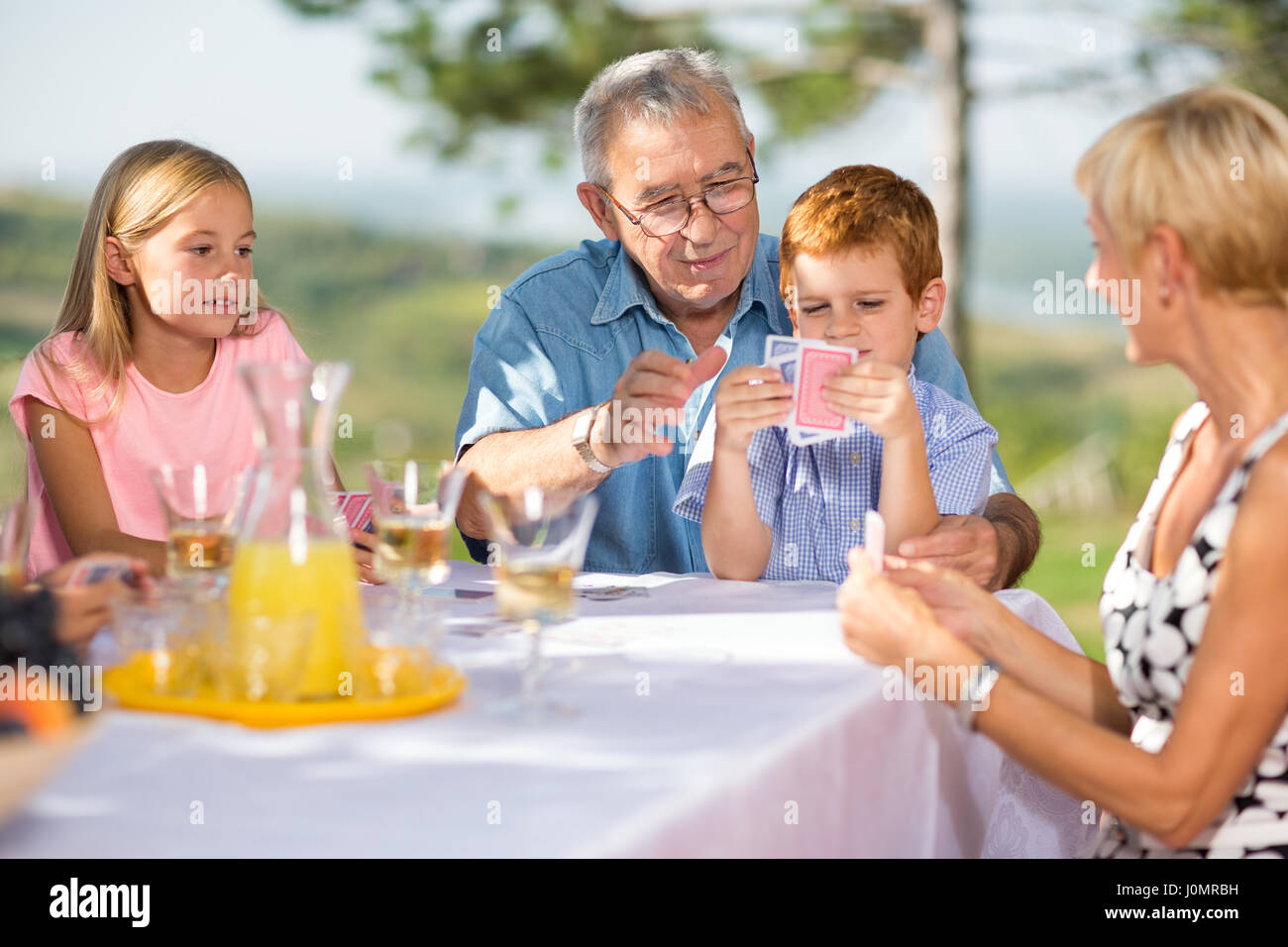 Nonno divertirsi a giocare a carte di gioco con i nipoti Foto Stock