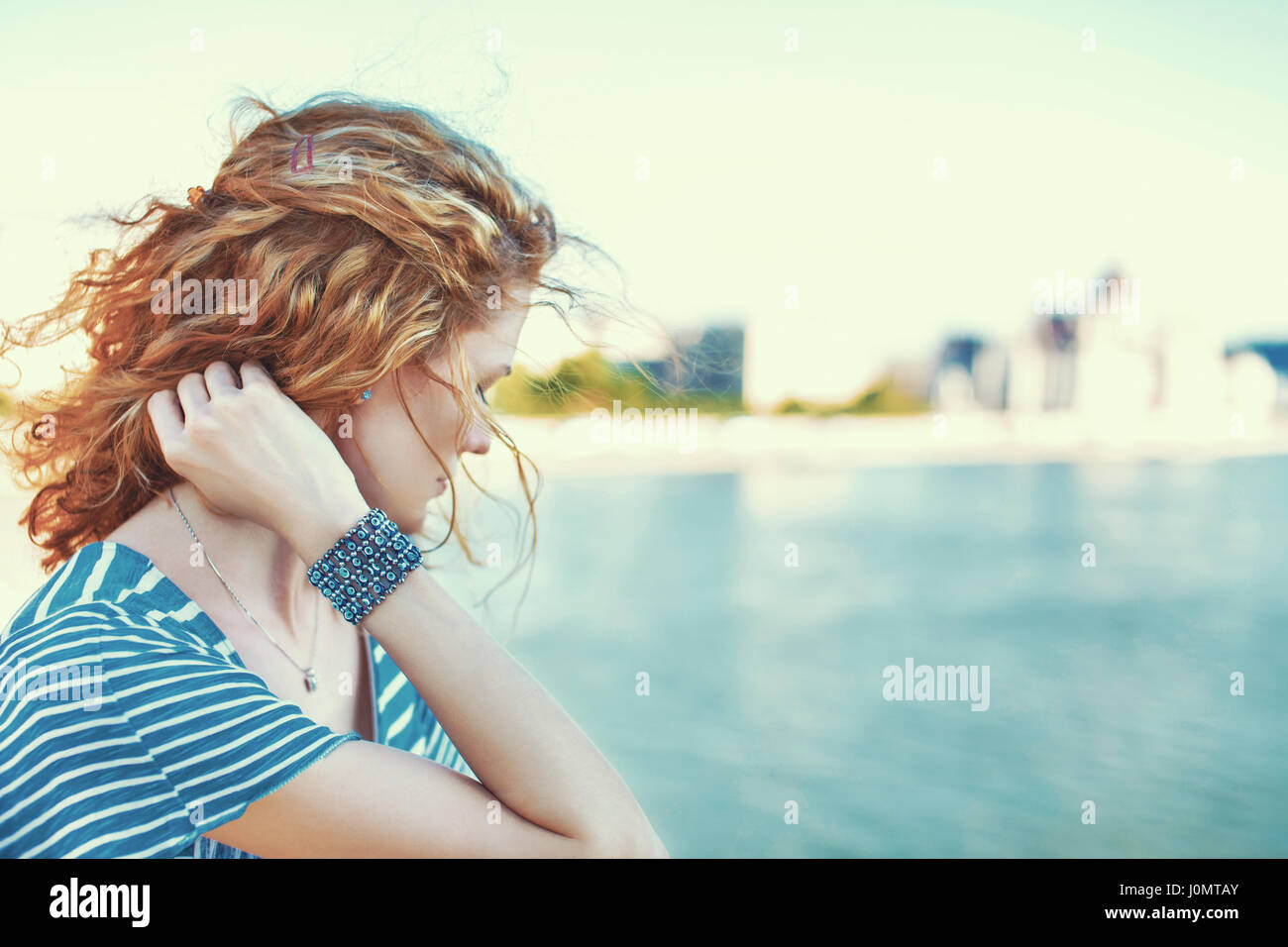 Triste redhead donna che guarda lontano oltre il fiume outdoor Foto Stock