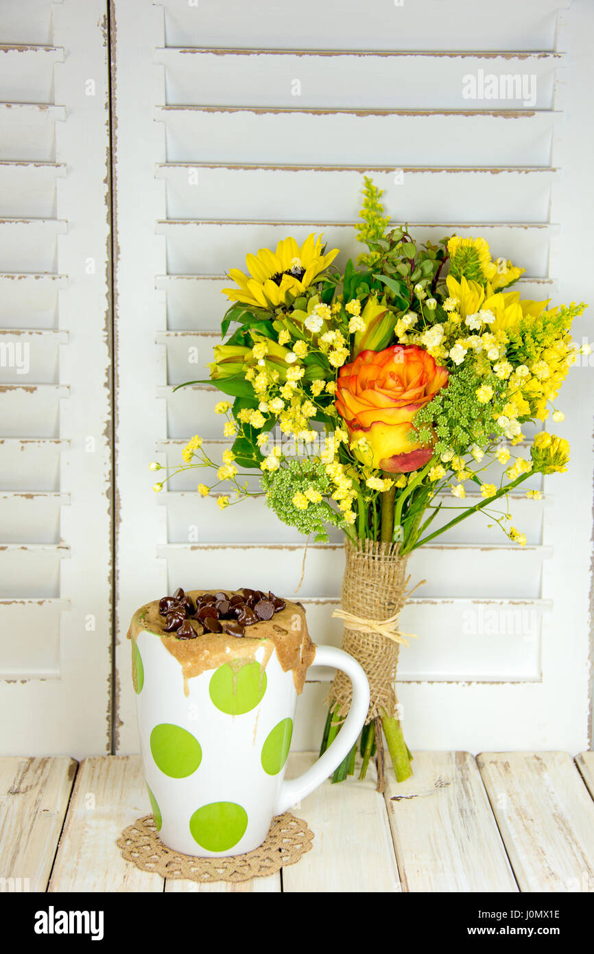 Chocolate Chip muffin cotti in polka dot la tazza con il bouquet floreale avvolto in tela Foto Stock