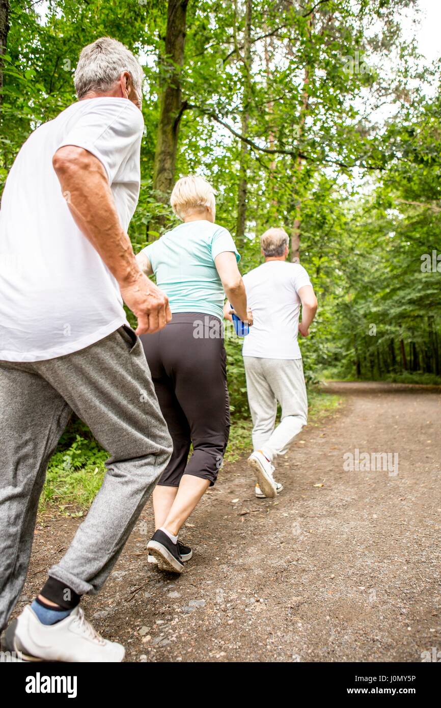 Tre persone in esecuzione sulla via di boschi. Foto Stock