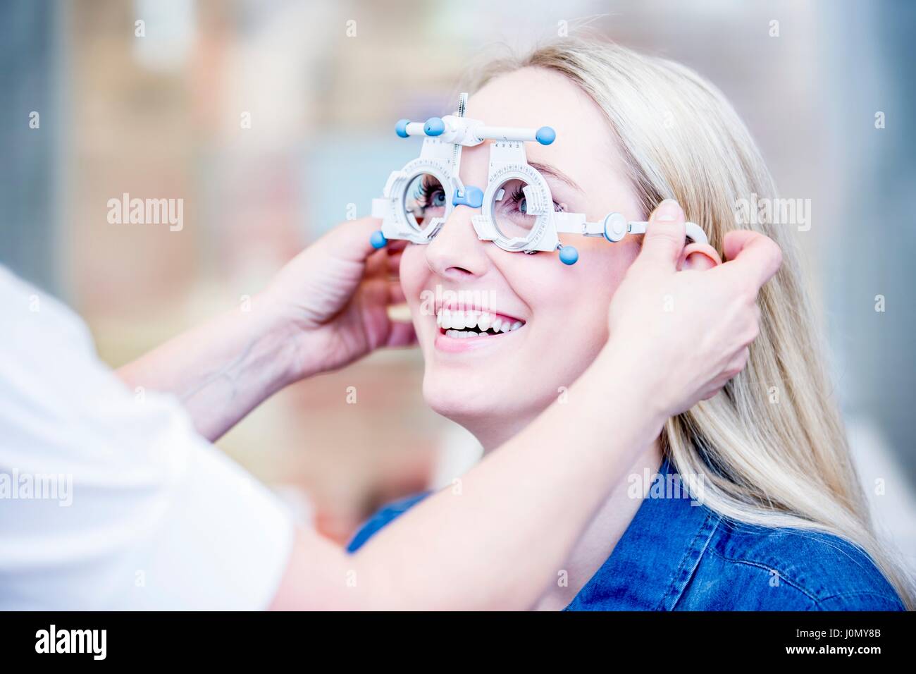 Allegro giovane donna con occhio esame eseguito da all'ottico optometrista. Foto Stock