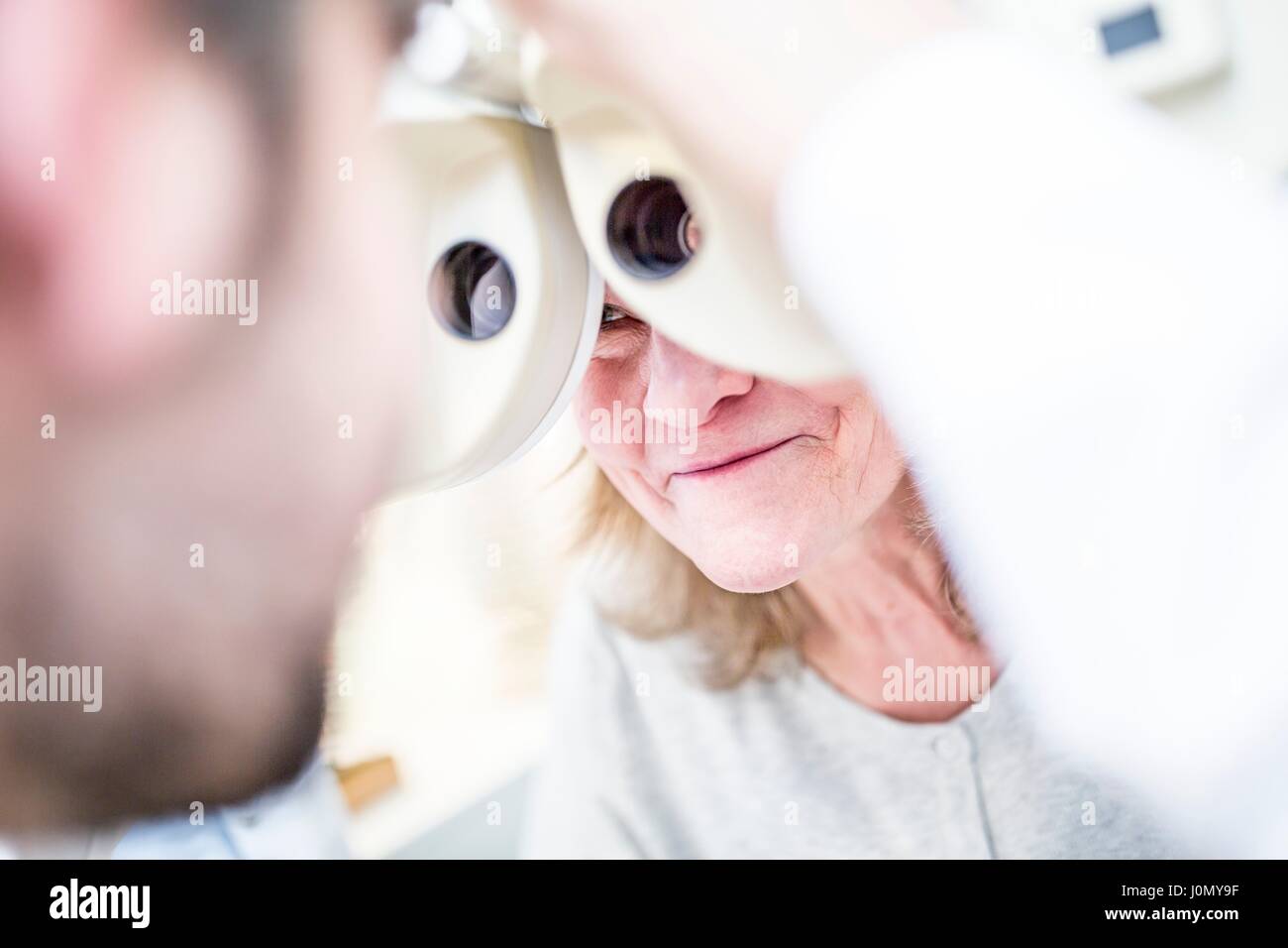 All'ottico optometrista eseguendo la prova degli occhi di donna senior con phoropter in all'ottico optometrista del negozio. Foto Stock