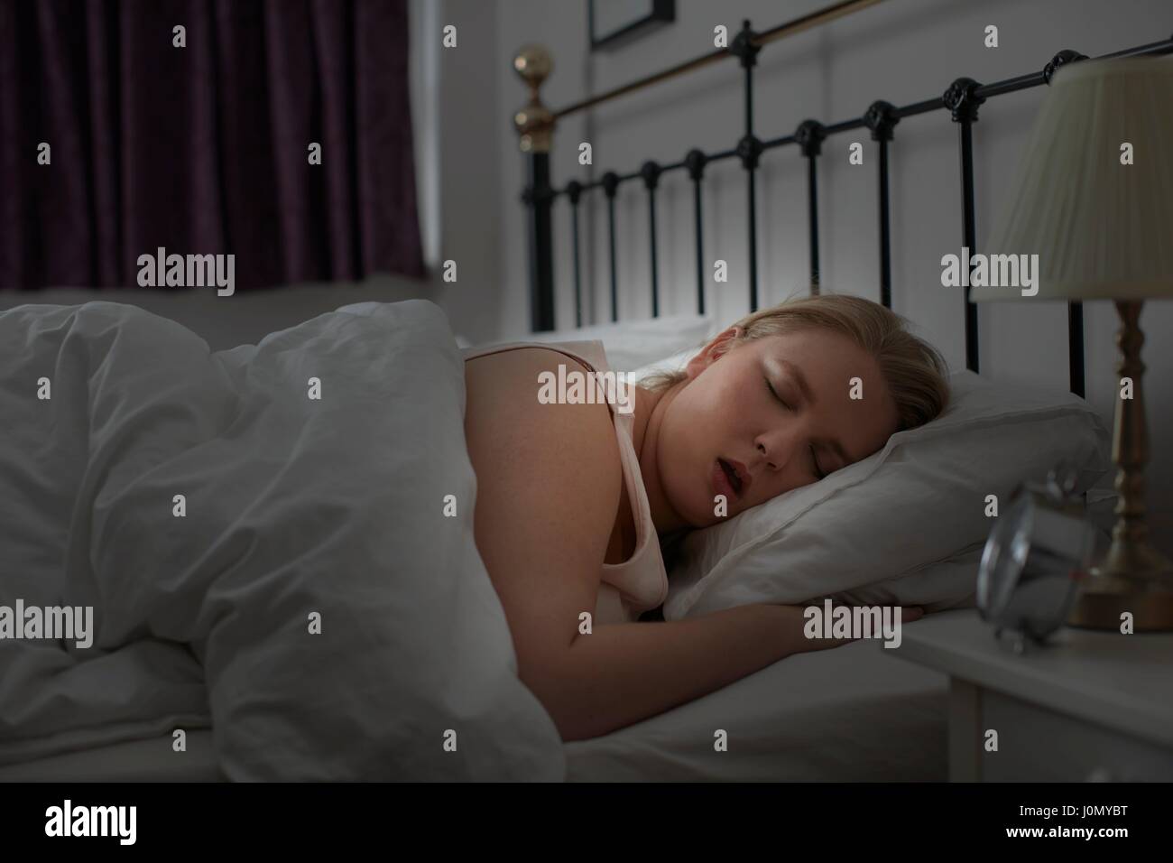 Giovane donna addormentata nel letto. Foto Stock