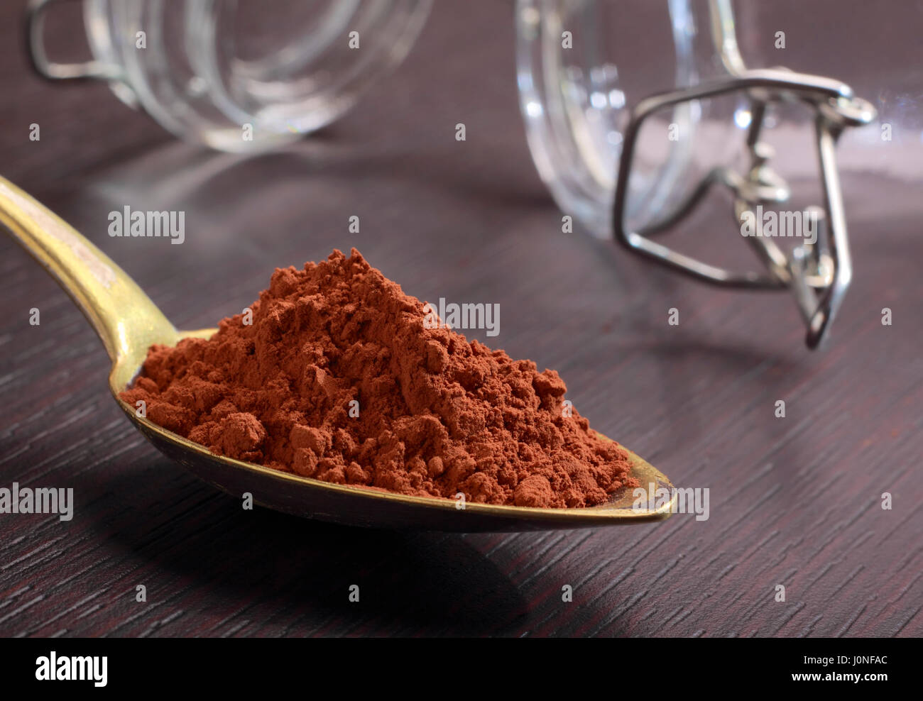 Ottone antico cucchiaio colmo di cacao in polvere sul bordo scuro Foto Stock