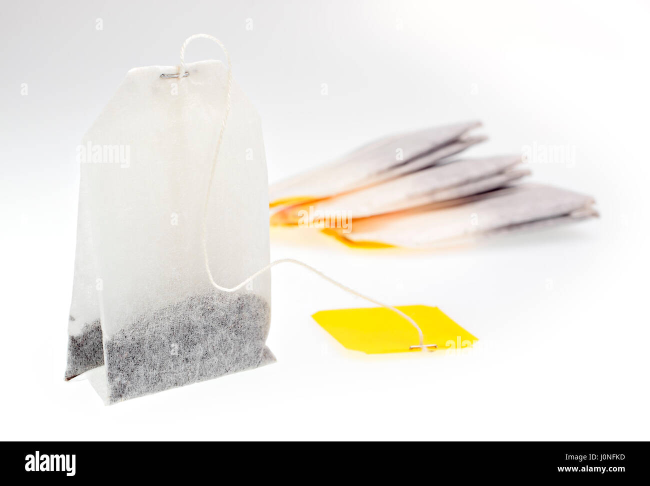 Bustine di tè con etichetta gialla su sfondo chiaro Foto Stock