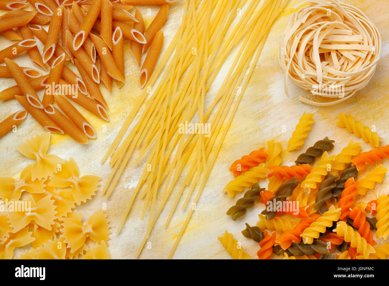 Varietà di asciugare la pasta grezza sopra dipinta sullo sfondo tessili. Vista aerea. Foto Stock