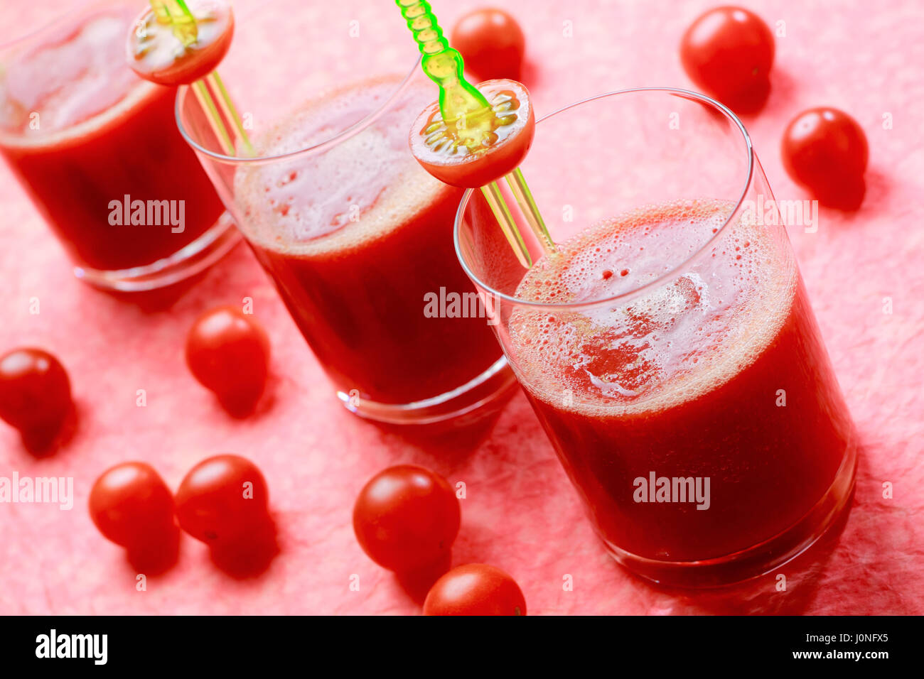 Tre Bicchieri con freschi succhi di pomodoro con pomodori ciliegia. Focus sul primo vetro. Foto Stock