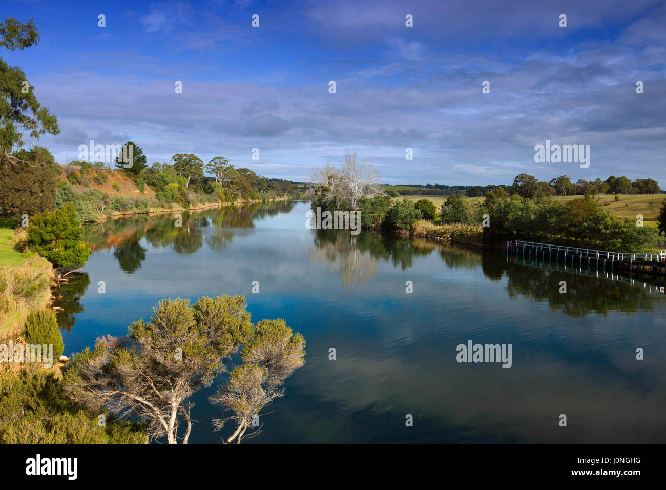 Incredibile paesaggio australiano con cielo blu e nuvole riflettono in superficie a specchio del Fiume Murray orlate da terreni coltivati nei pressi di Swan raggiungere, Victoria Foto Stock