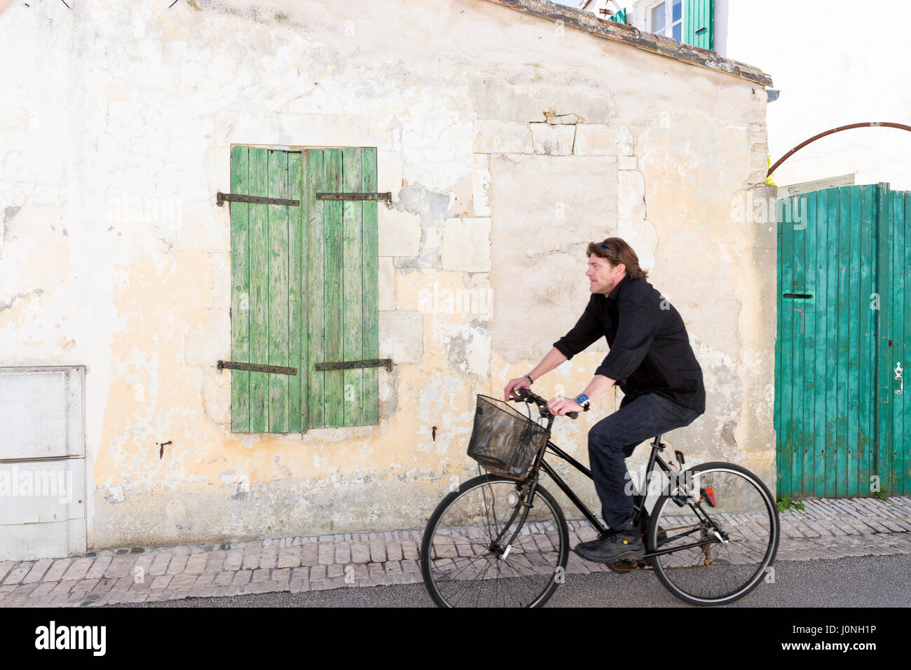 Uomo Bicicletta Equitazione passato persiane di legno in Les Portes en Re, Ile de Re, Francia Foto Stock