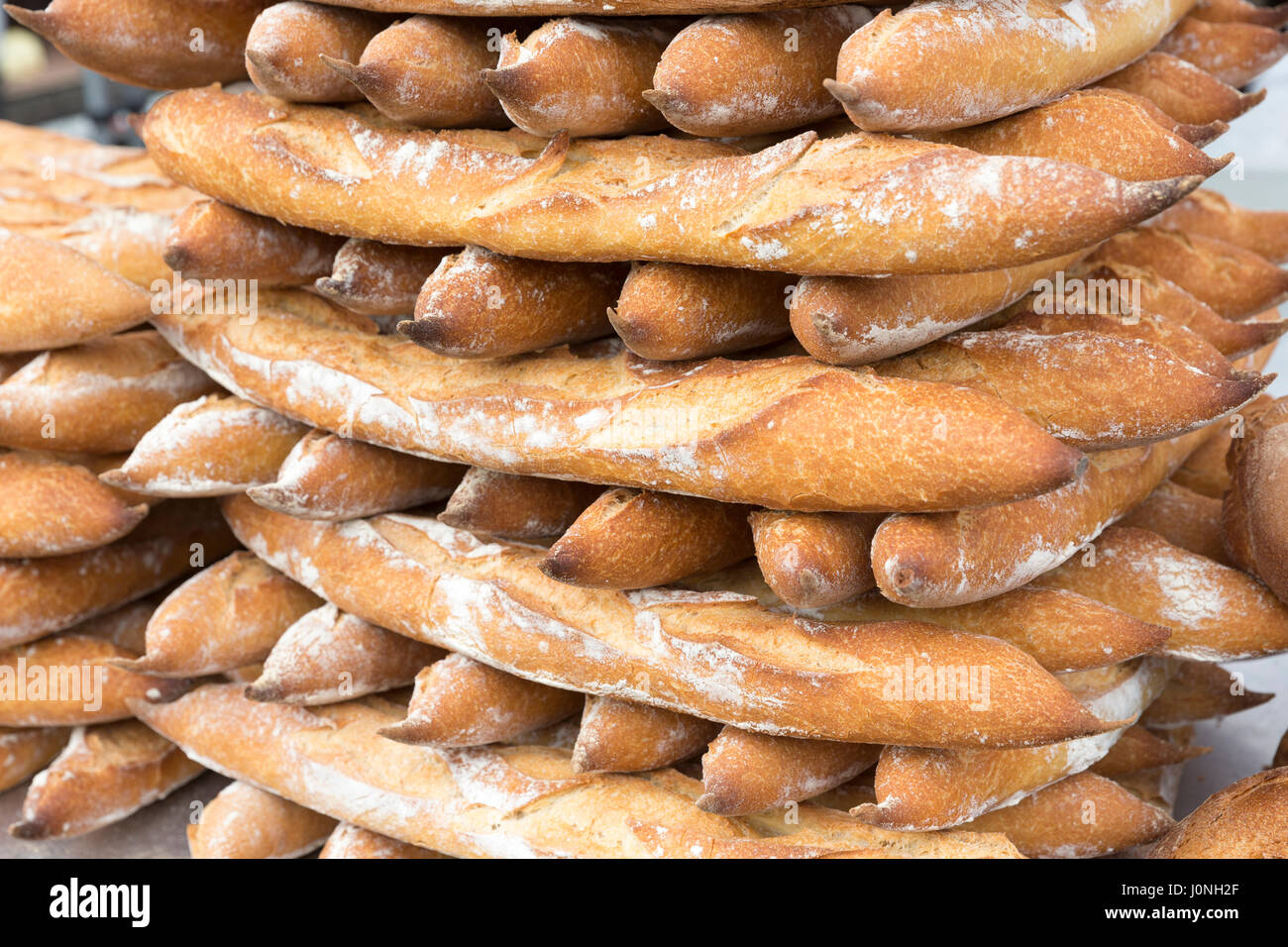 Francese impilati freschi di forno pani baguette di pane tra i prodotti alimentari in vendita al mercato di strada Bordeaux, Francia Foto Stock