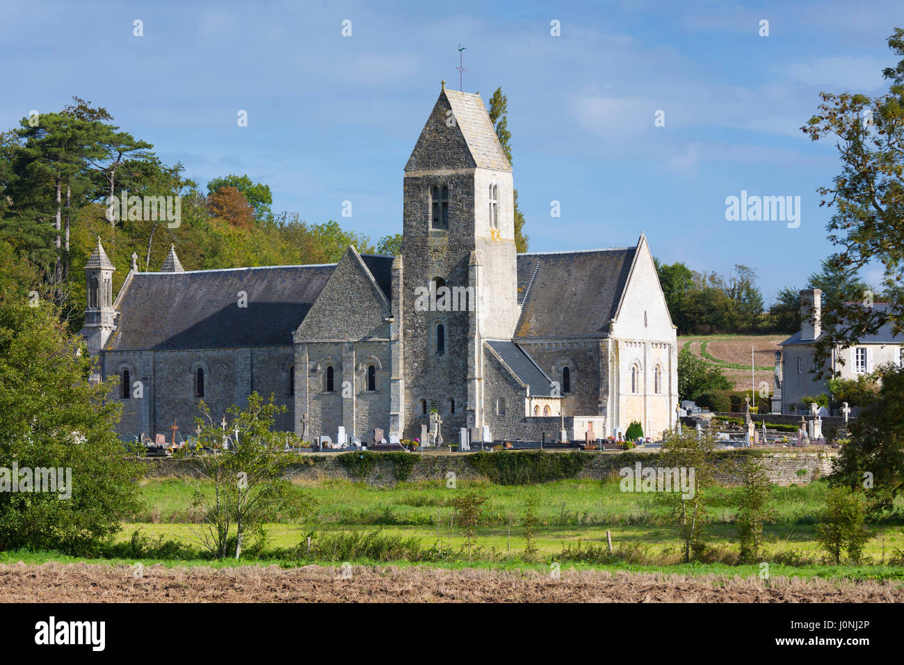 Antico tipico stile normanno chiesa con tombe nel cimitero nel villaggio di Vaux-sur-Aure in Normandia Foto Stock