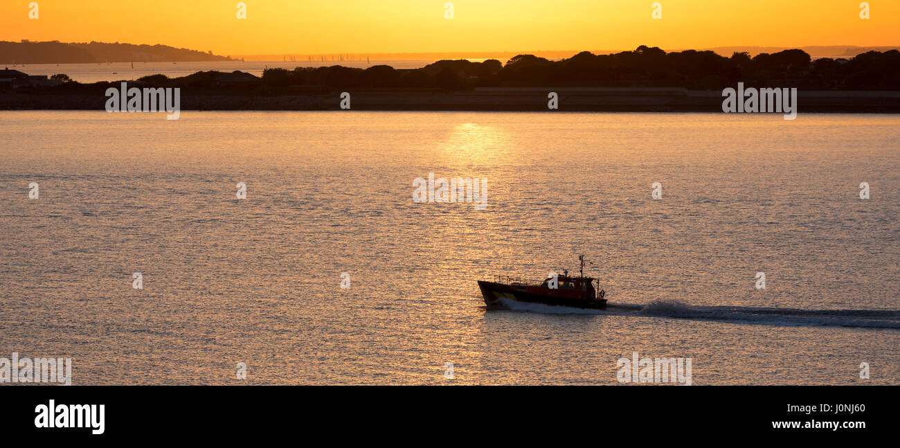 Imbarcazione a motore in mare al tramonto dal fiume Solent, Regno Unito Foto Stock