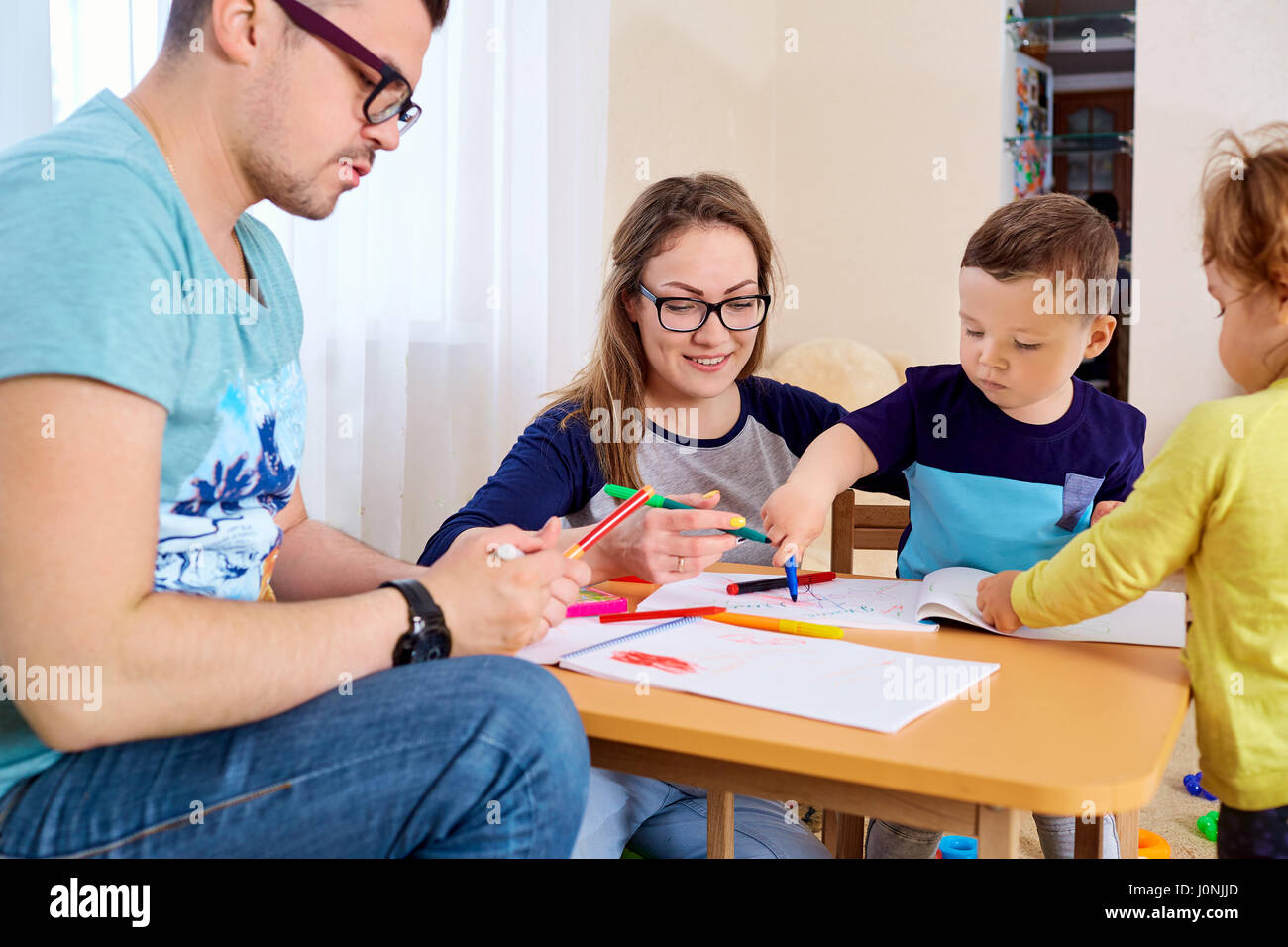 I genitori e i bambini disegnare insieme in camera Foto Stock