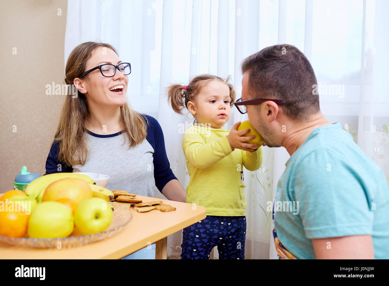 La figlia alimenta il suo papà con un Apple in camera Foto Stock