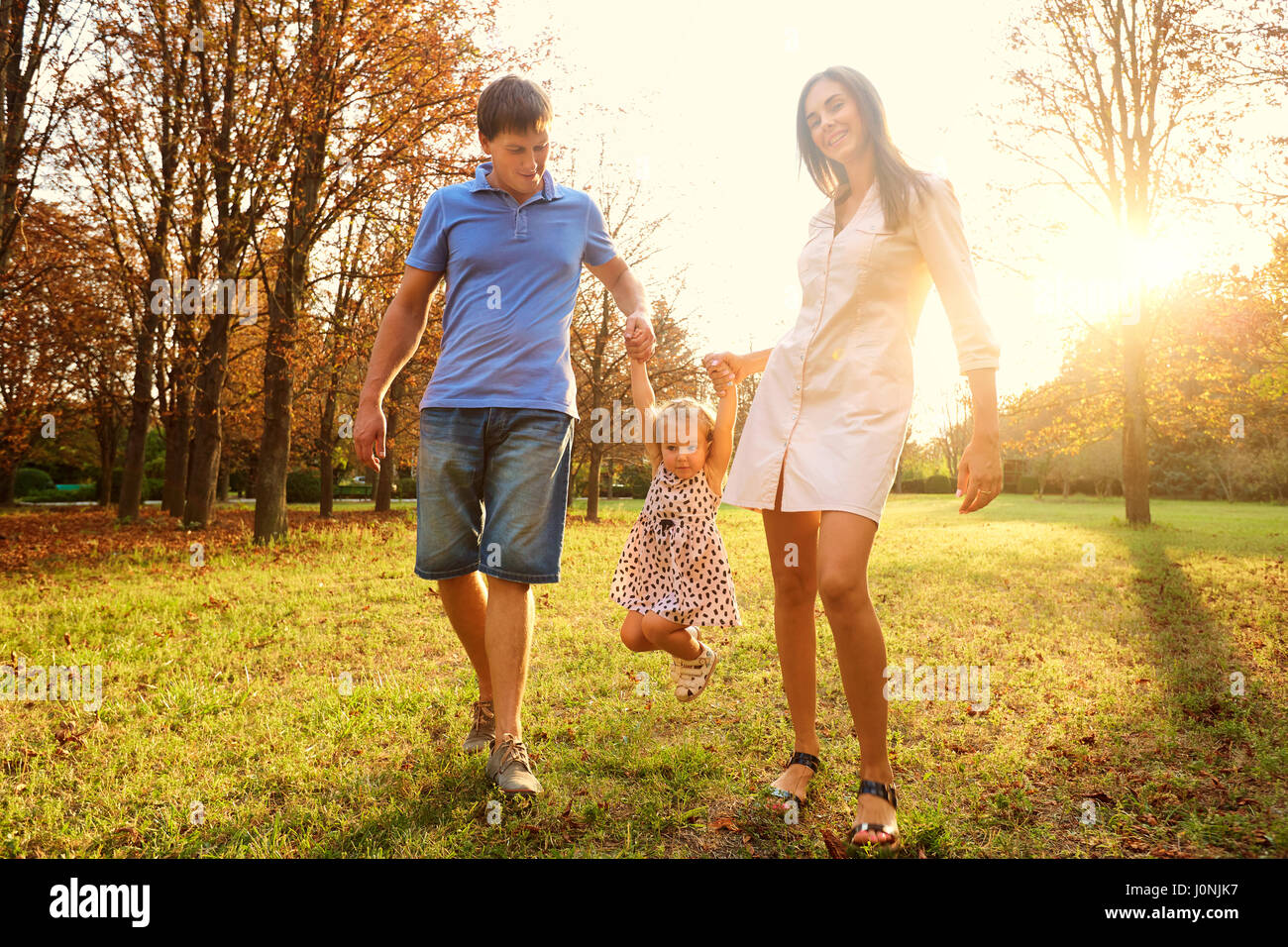 Famiglia giocare nel parco del sole al tramonto Foto Stock