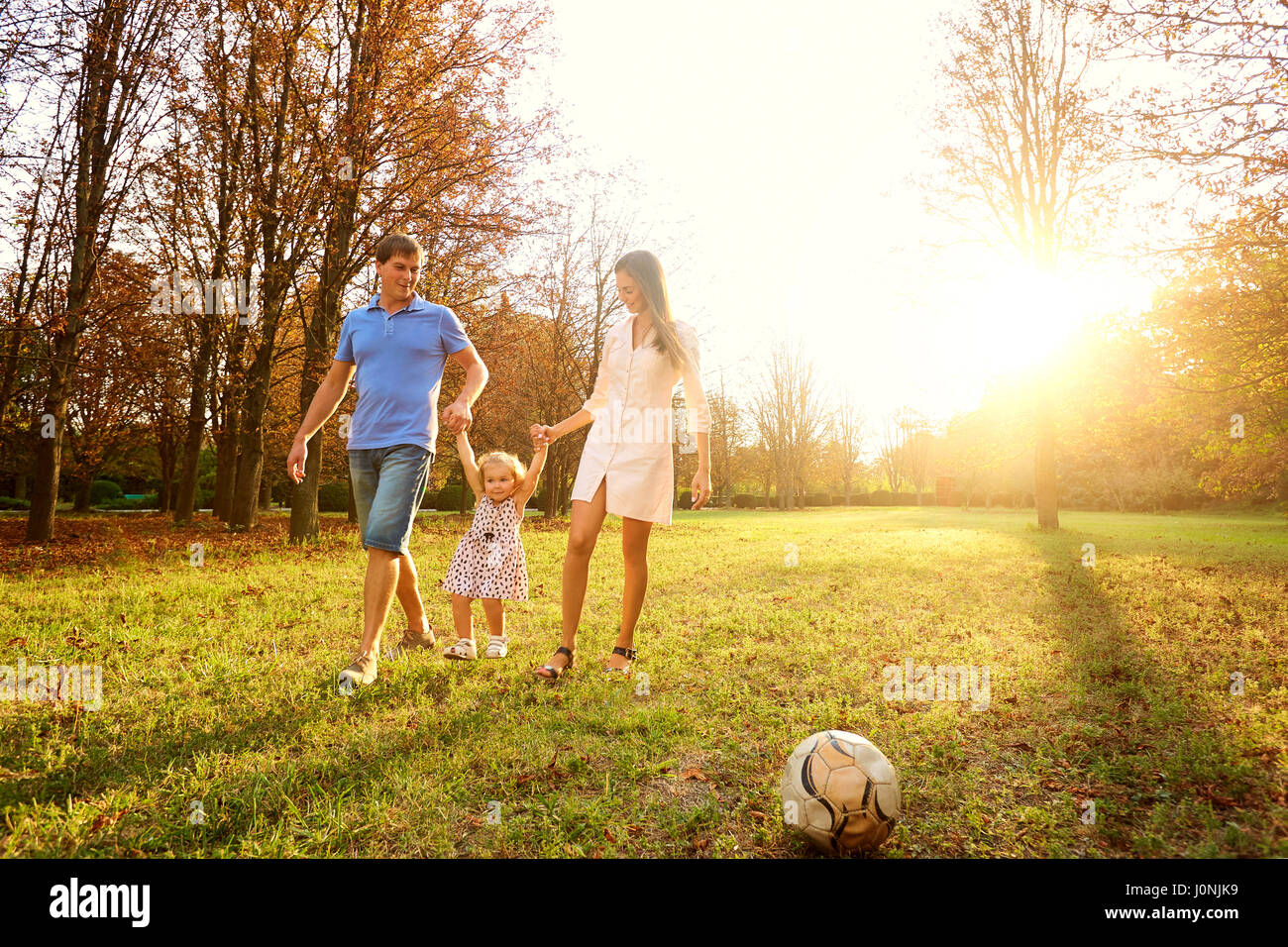 Famiglia giocare nel parco del sole al tramonto Foto Stock