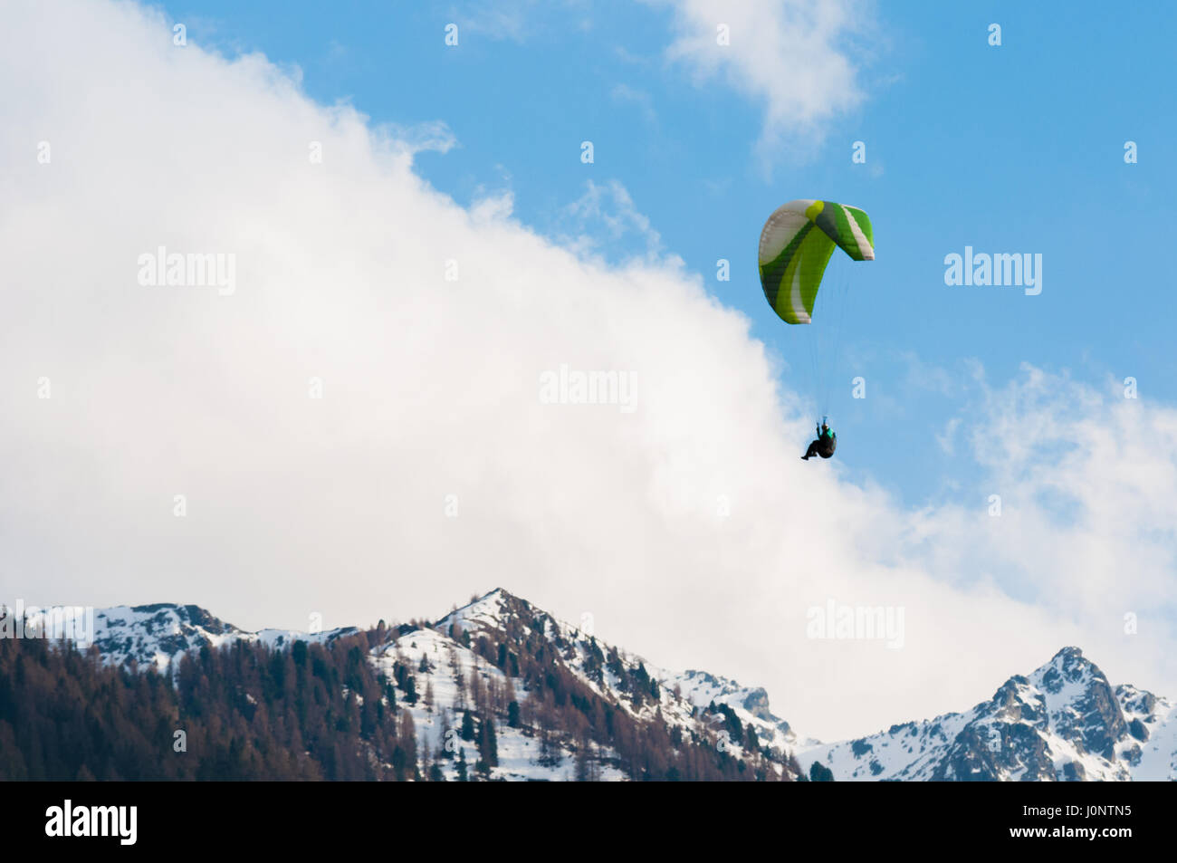 Parapendio volare nel cielo blu tra le nuvole e sulle montagne Foto Stock