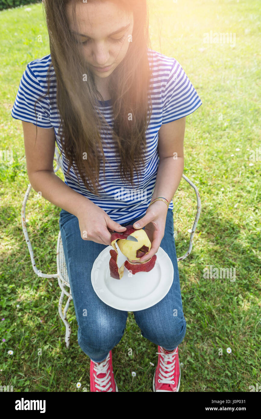 Giovane donna peeling un Apple in giardino Foto Stock