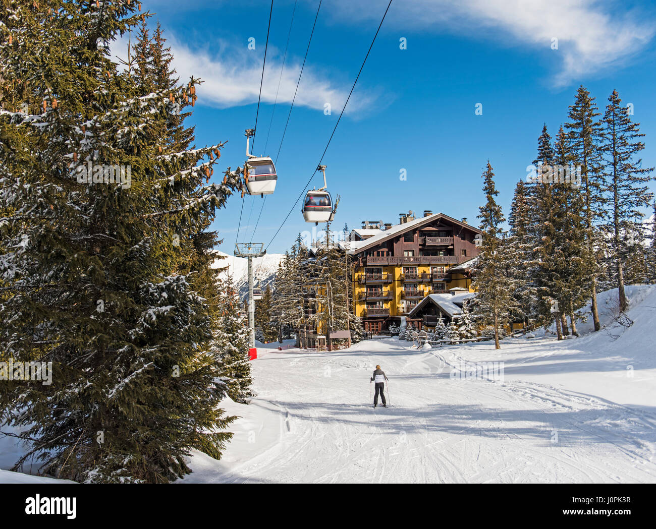 Sciatore su una neve piste da sci piste da sci in inverno alpine resort di montagna con boschi di conifere di alberi di pino e hotel Foto Stock