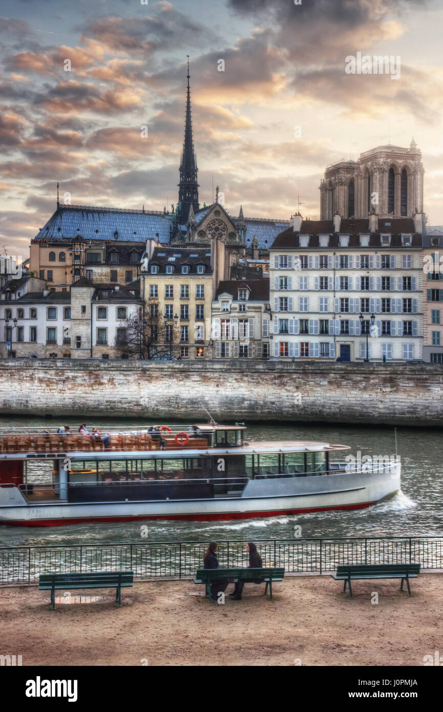 Due ragazze sul quai de l'Hôtel de Ville e nave turistica, affacciato sul quai Bourbon e Notre Dame. La Francia. Parigi Foto Stock