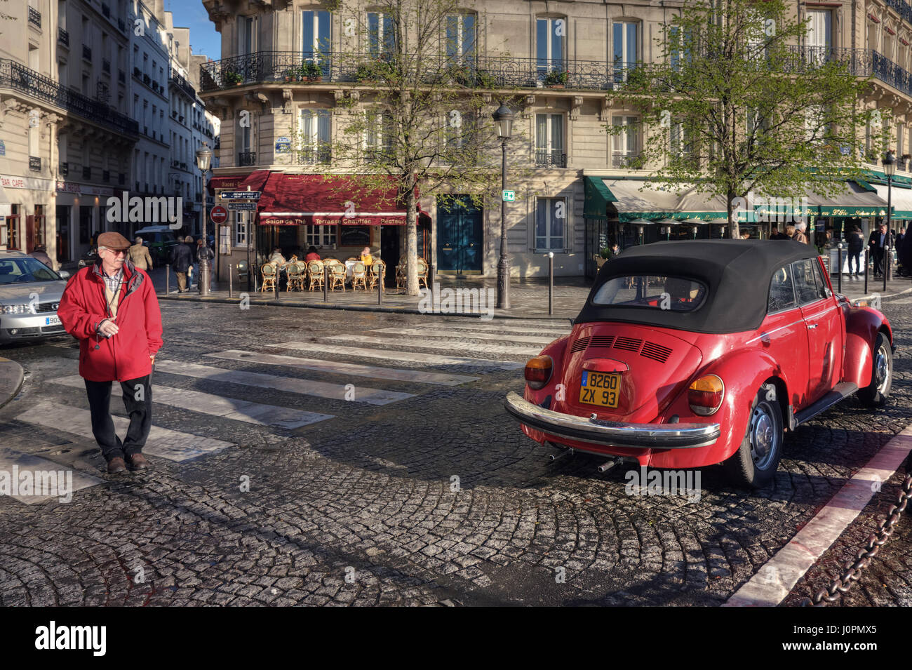 Un anziano turista in una giacca rossa balade passato un rosso vecchia auto. Crocevia di rue Saint-Louis en l'Île, Rue Jean Du Bellay e Quai de Bourbon. La Francia. Foto Stock