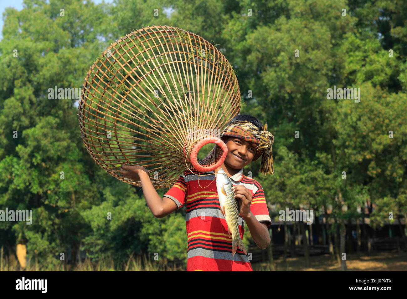 Un ragazzo detiene una trappola di pesca localmente chiamato Polo. Gazipur, Bangladesh Foto Stock
