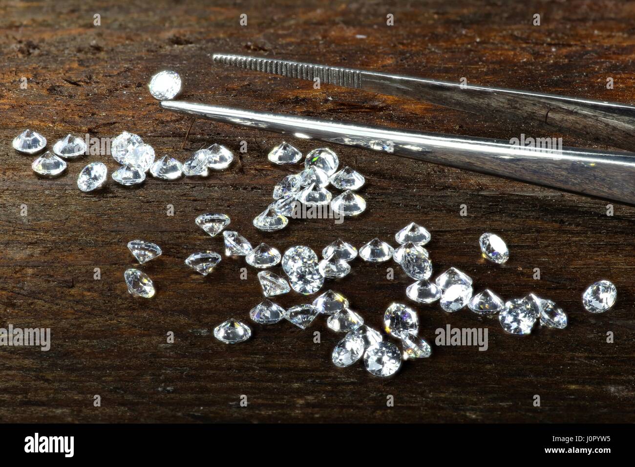 Diamanti taglio brillante con pinzette su sfondo di legno Foto Stock