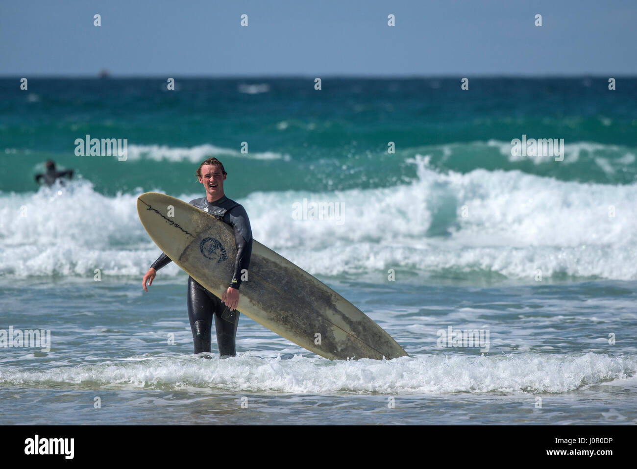 Regno Unito surfing Fistral Newquay Surfer lasciando il mare a piedi al di fuori del mare con la tavola da surf Surf Watersport turismo balneare Beach Foto Stock