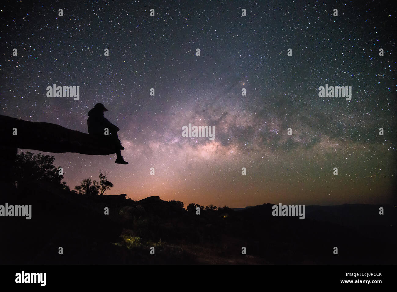 La donna siede su pietra lodge e guardare il cielo notturno di stelle con via lattea sfondo Foto Stock