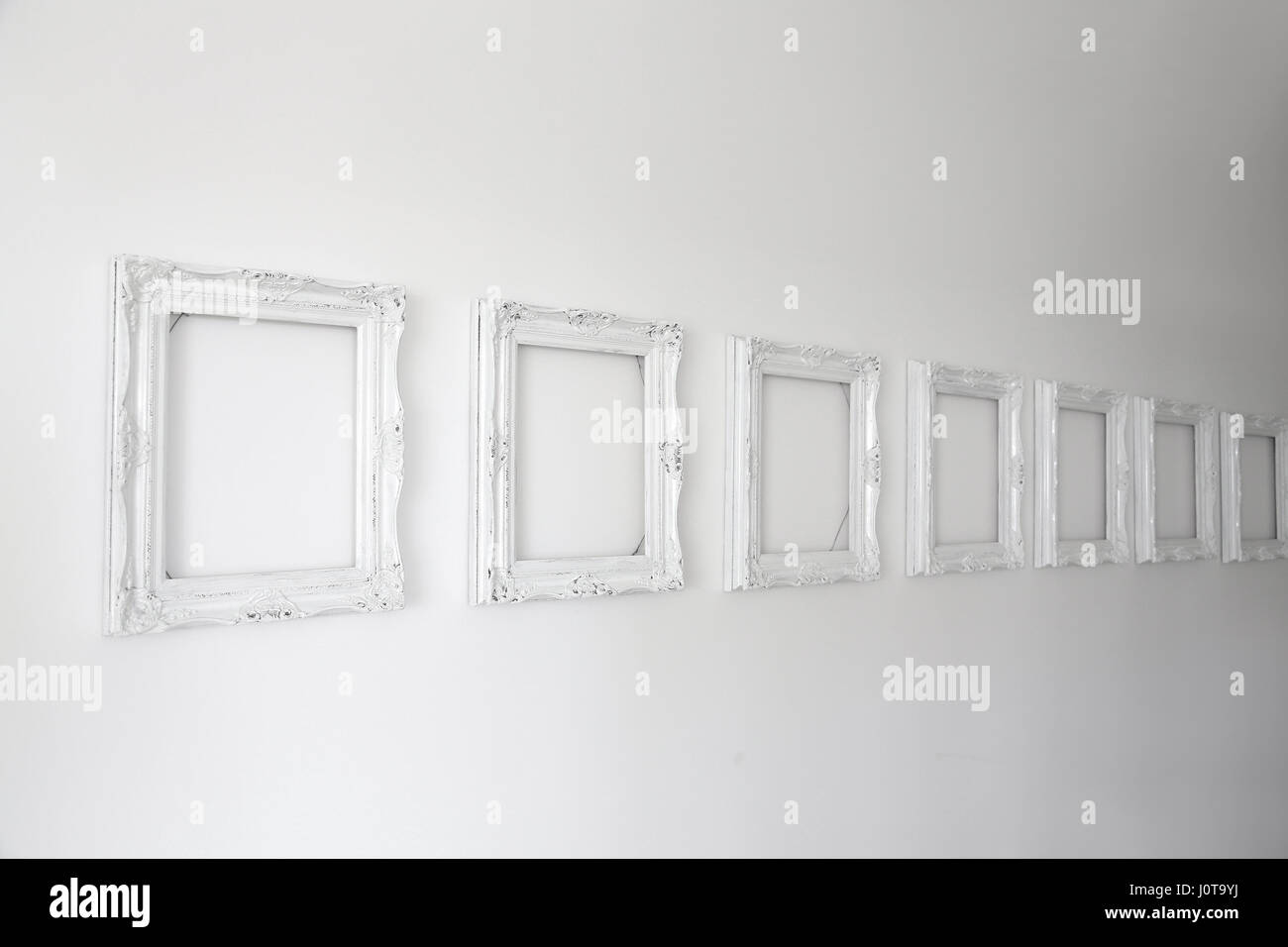 Vuoto cornici bianche sulla parete vuota Foto stock - Alamy