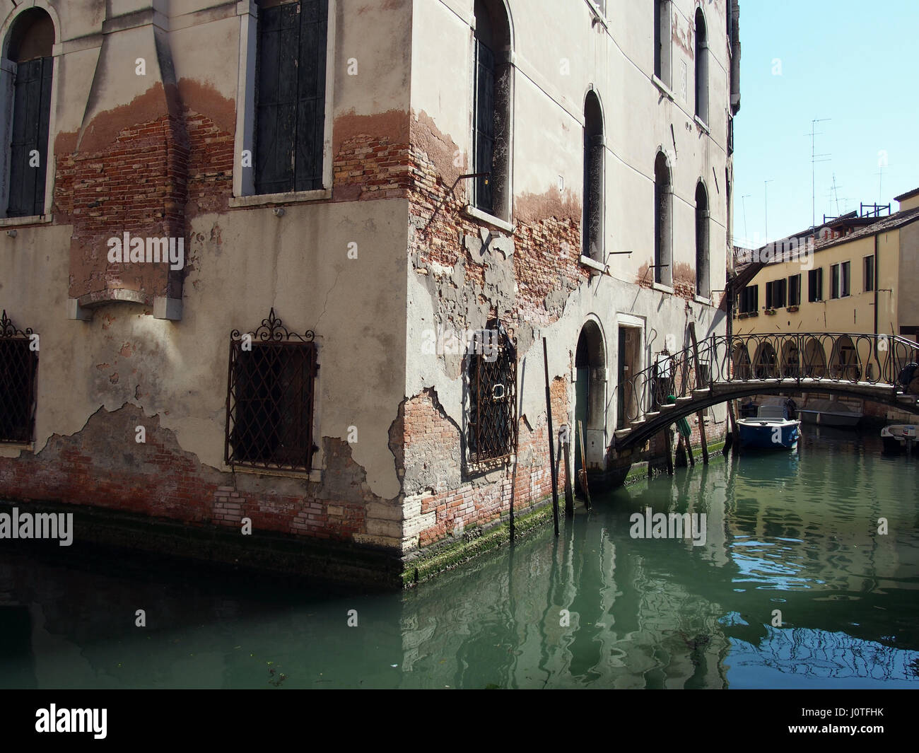Vecchio edificio su un canale di Venezia con il piccolo ponte Foto Stock