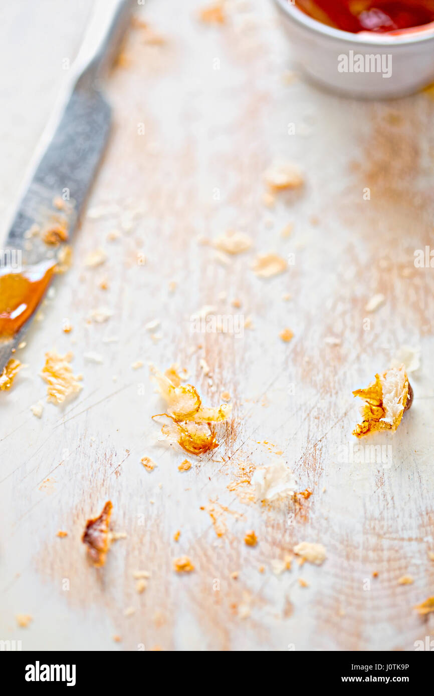 Tavola di legno dopo il pasto finito con le briciole, coltello e ramekin con ketchup Foto Stock