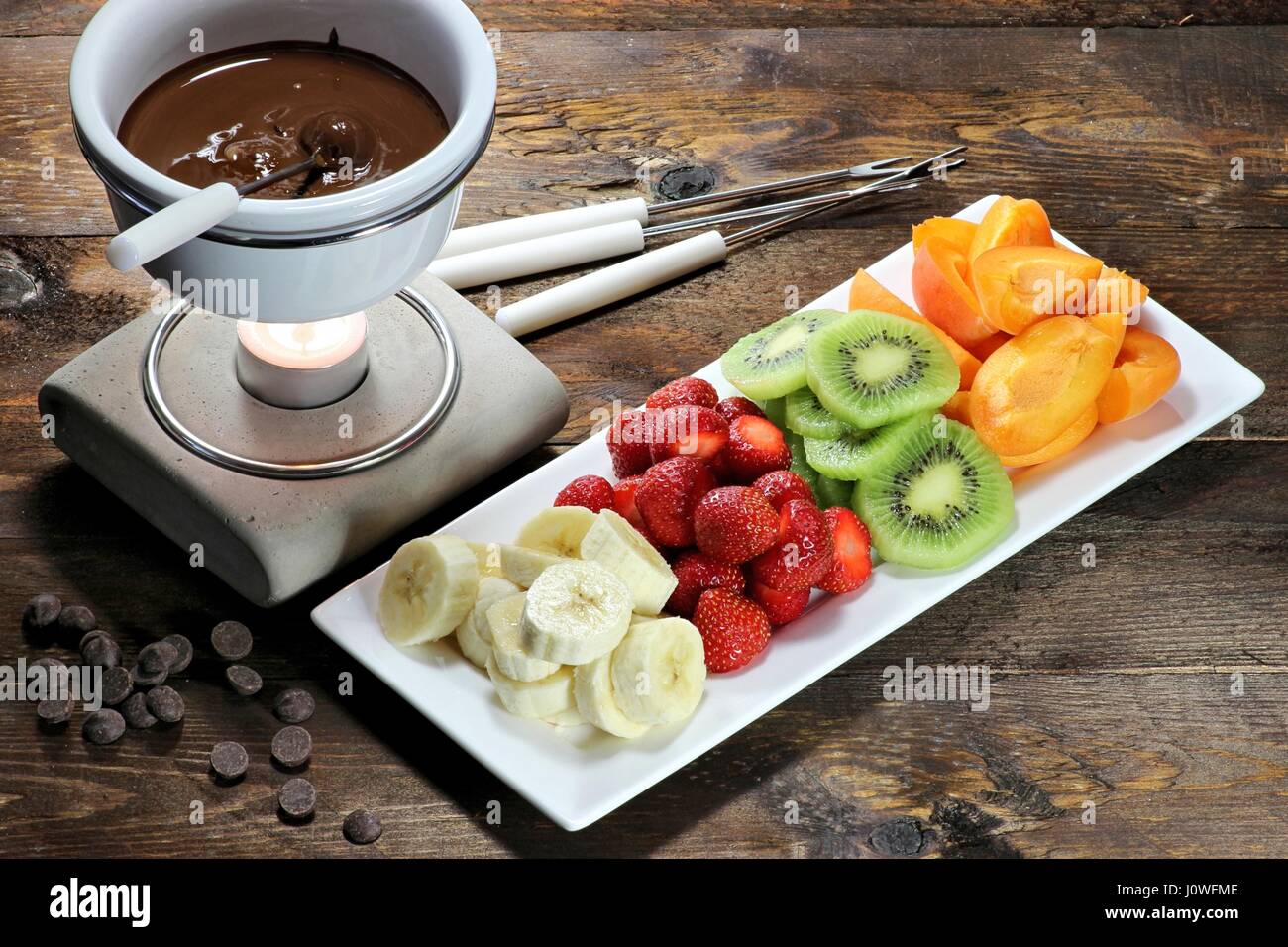 La Fonduta di cioccolato con frutta assortimento su sfondo di legno Foto Stock
