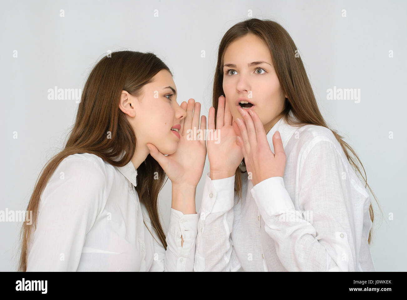 Giovane ragazza di pettegolezzo sussurrare al suo amico l orecchio Foto Stock