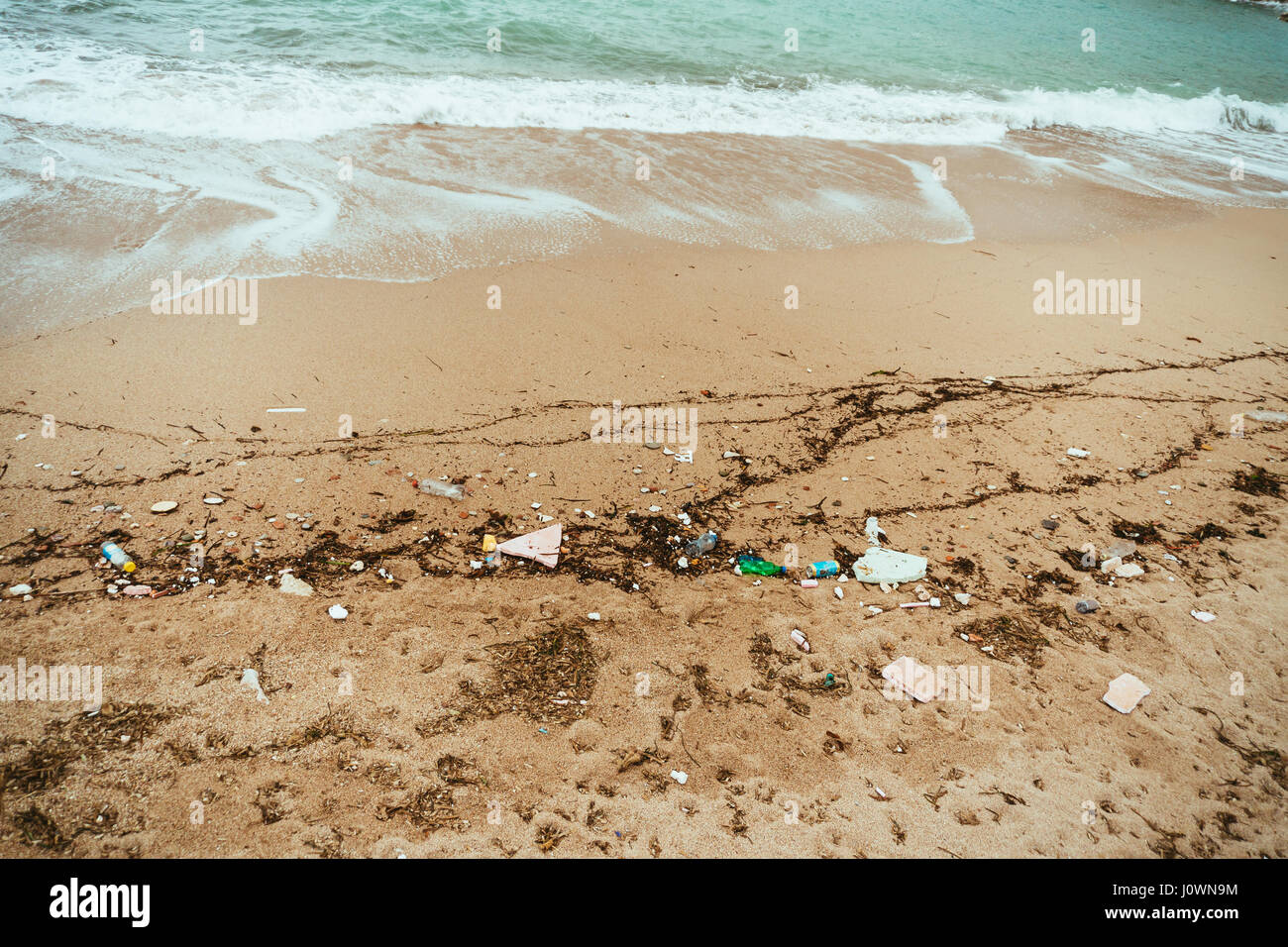 La riva del mare nella spazzatura. Inquinamento ambientale. Immondizia sulla spiaggia sabbiosa. Foto Stock