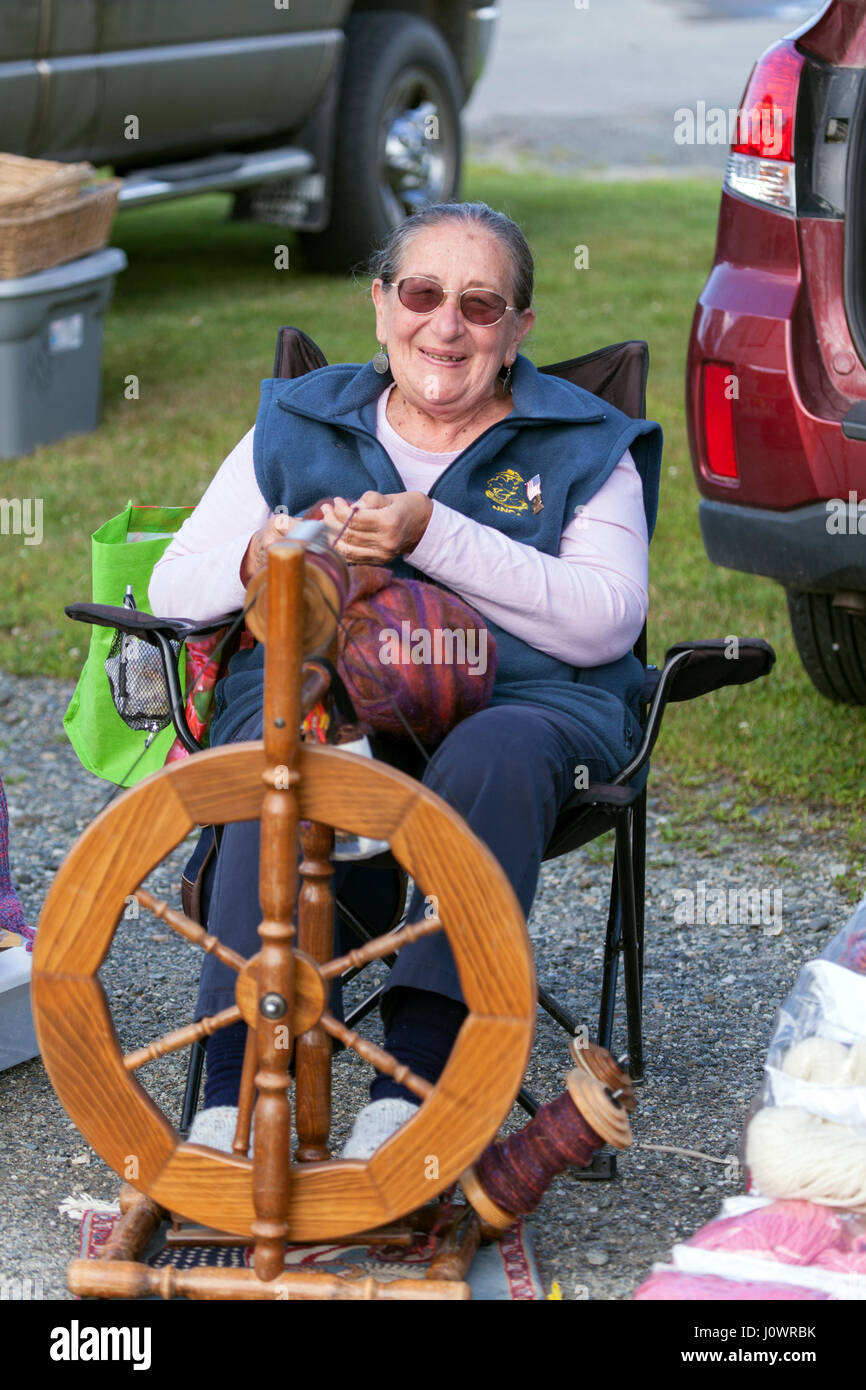 Un senior donna età rimanendo attivo partecipando nella sua città mercato di agricoltori con la sua ruota di filatura a Lisbona, New Hampshire, Stati Uniti. Foto Stock