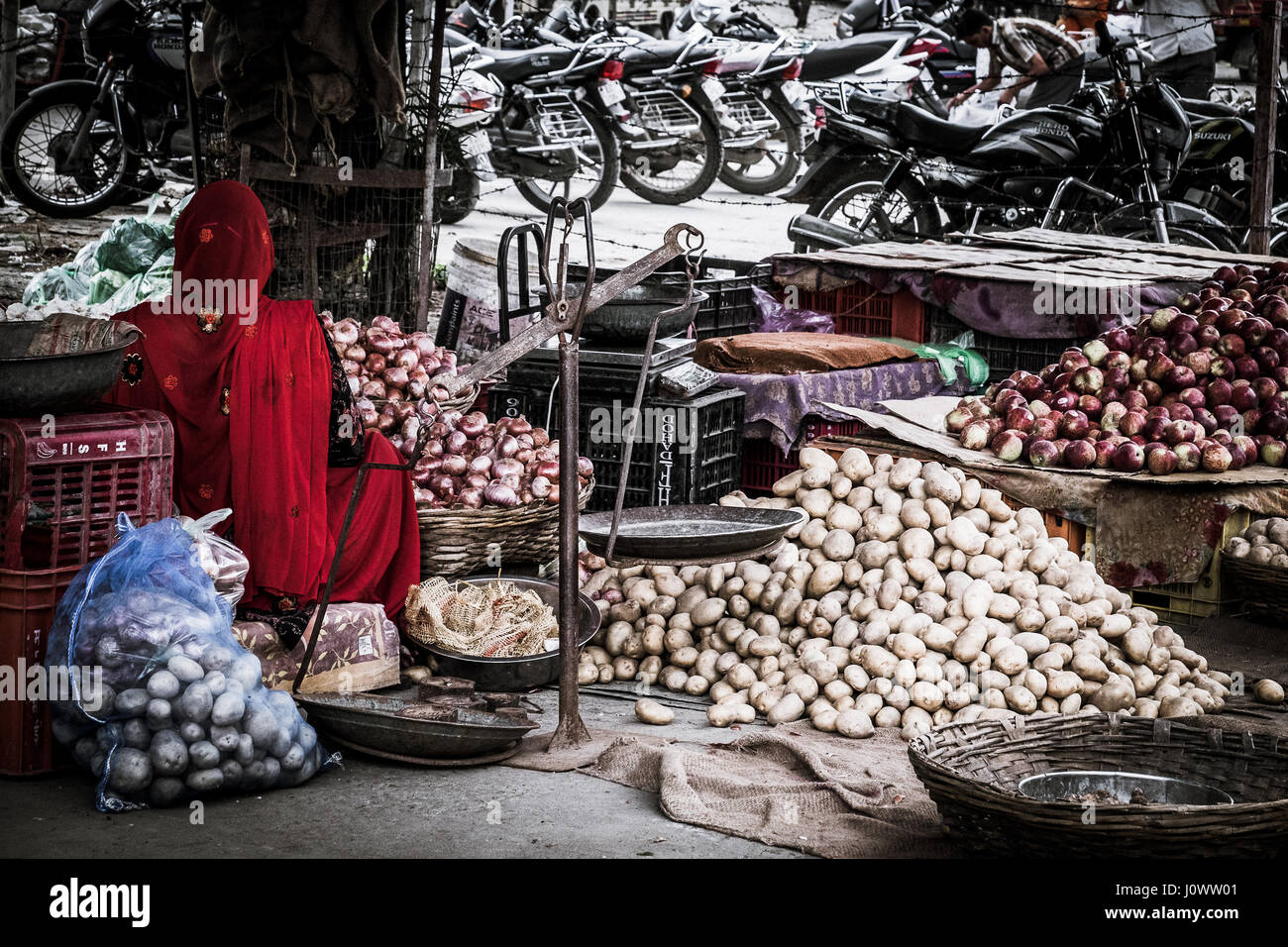 Stallo del mercato vendono patate in Udaipur, la signora in rosso sari & torna alla fotocamera Foto Stock