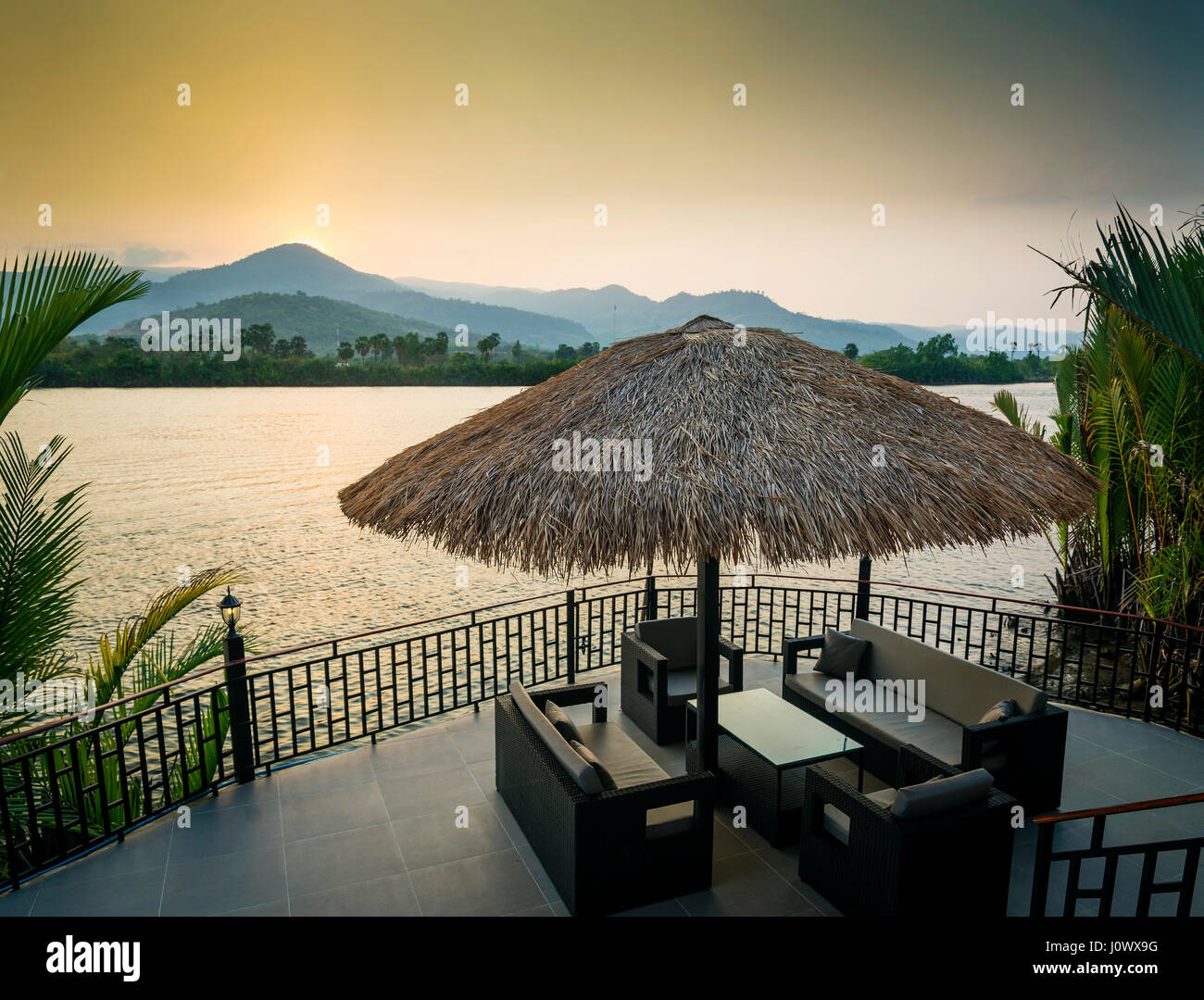 Riverside vista al tramonto in kampot cambogia asia con ponte di rilassanti divani sedie e tavolo Foto Stock