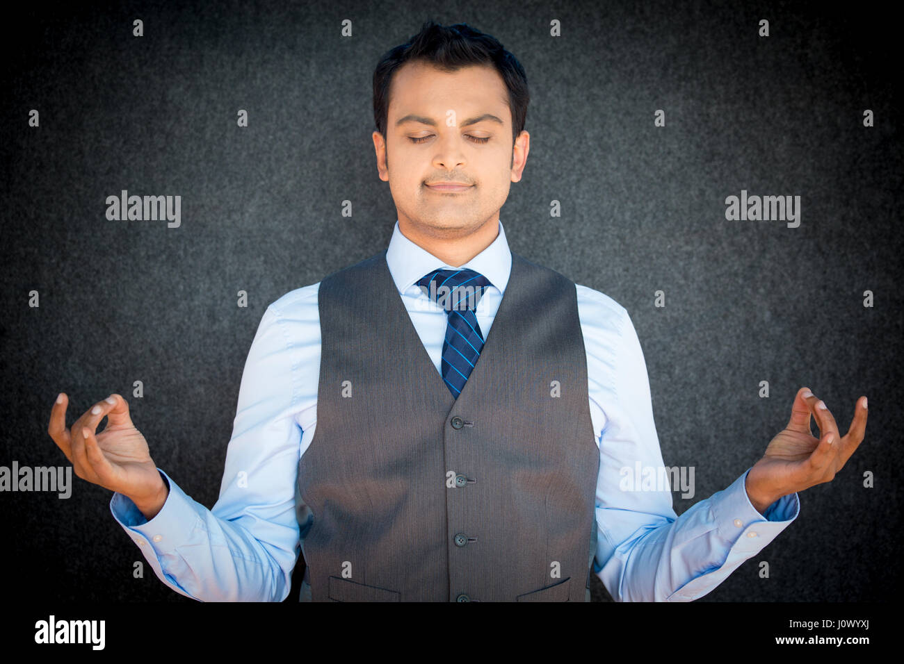Closeup ritratto di bello, giovane uomo in gilet e cravatta in meditazione modalità zen, isolato grigio sfondo nero. stress tecniche di rilievo del concetto. Foto Stock
