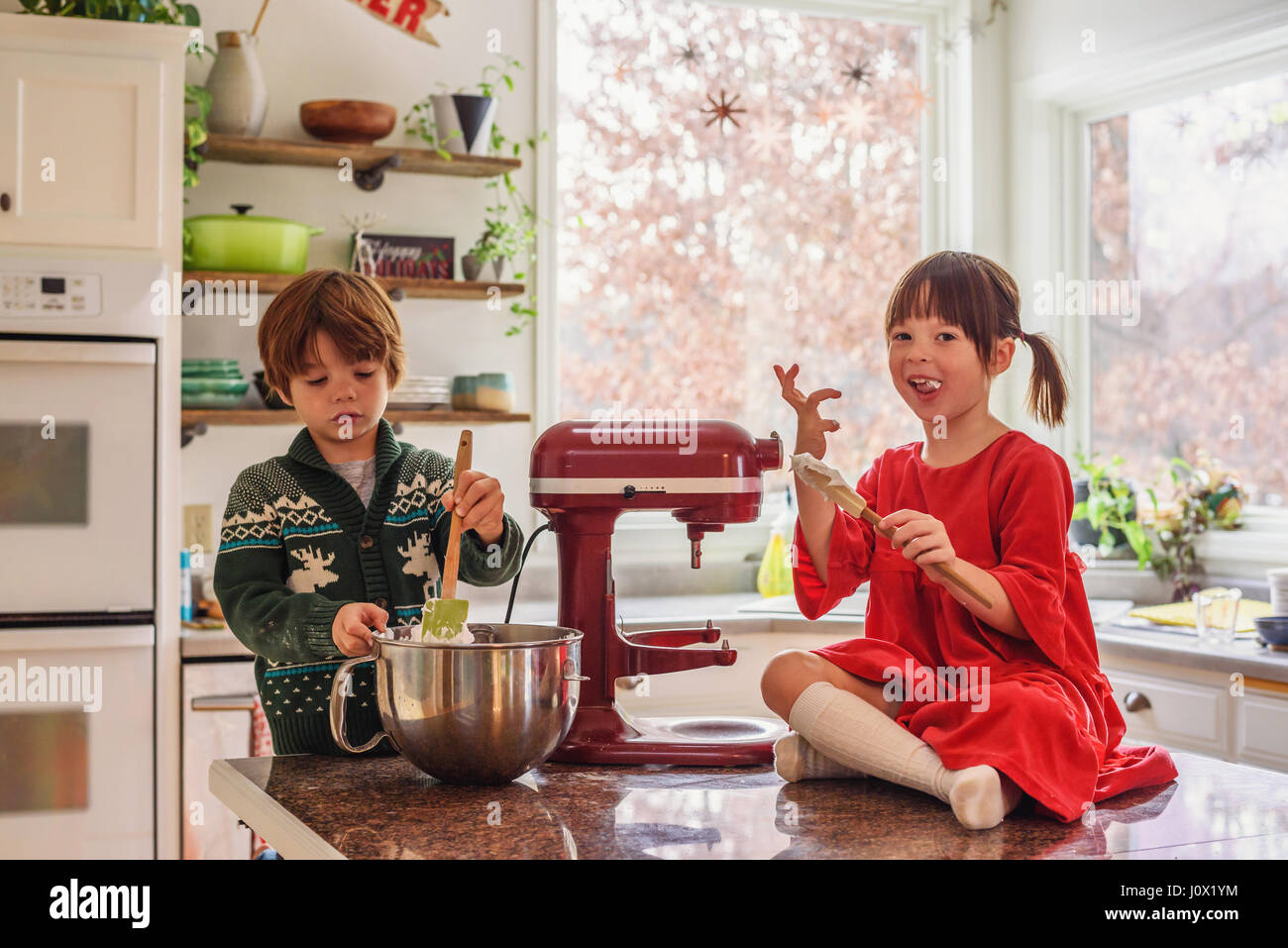 Due bambini aiutando cuocere i biscotti in forno insieme in cucina Foto Stock