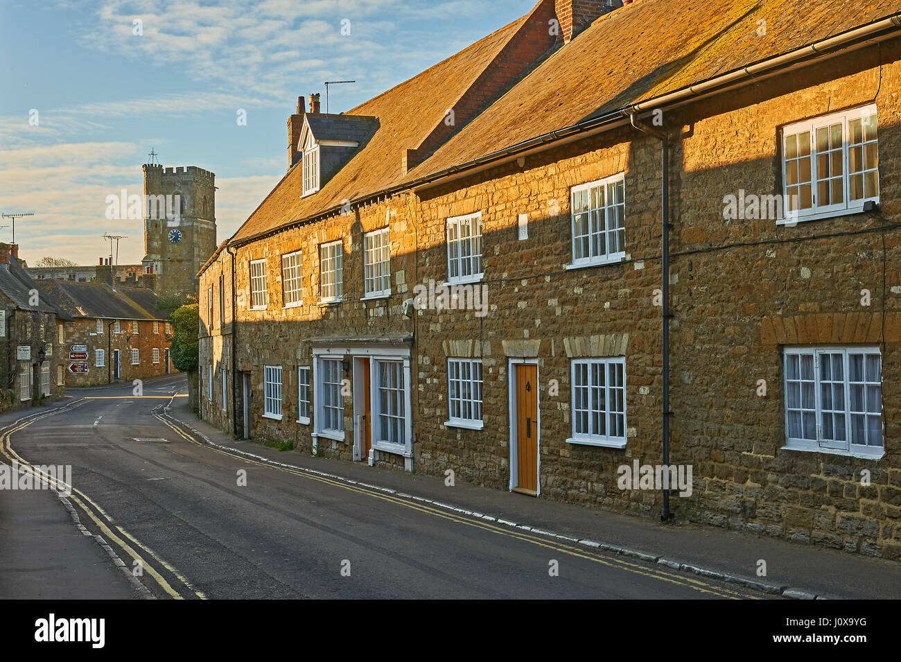 Scena di strada nel piccolo villaggio di Dorset di Abbotsbury con la strada che conduce verso la piccola chiesa di San Nicola. Foto Stock