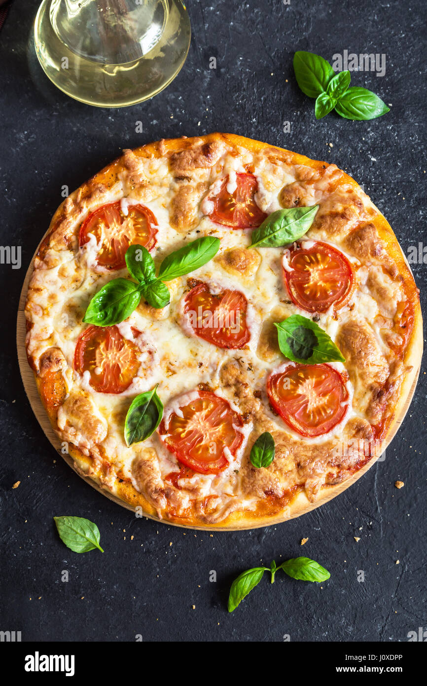 La Pizza Margherita sulla pietra nera dello sfondo. Pizza Margherita con pomodoro, basilico e mozzarella con copia spazio. Foto Stock