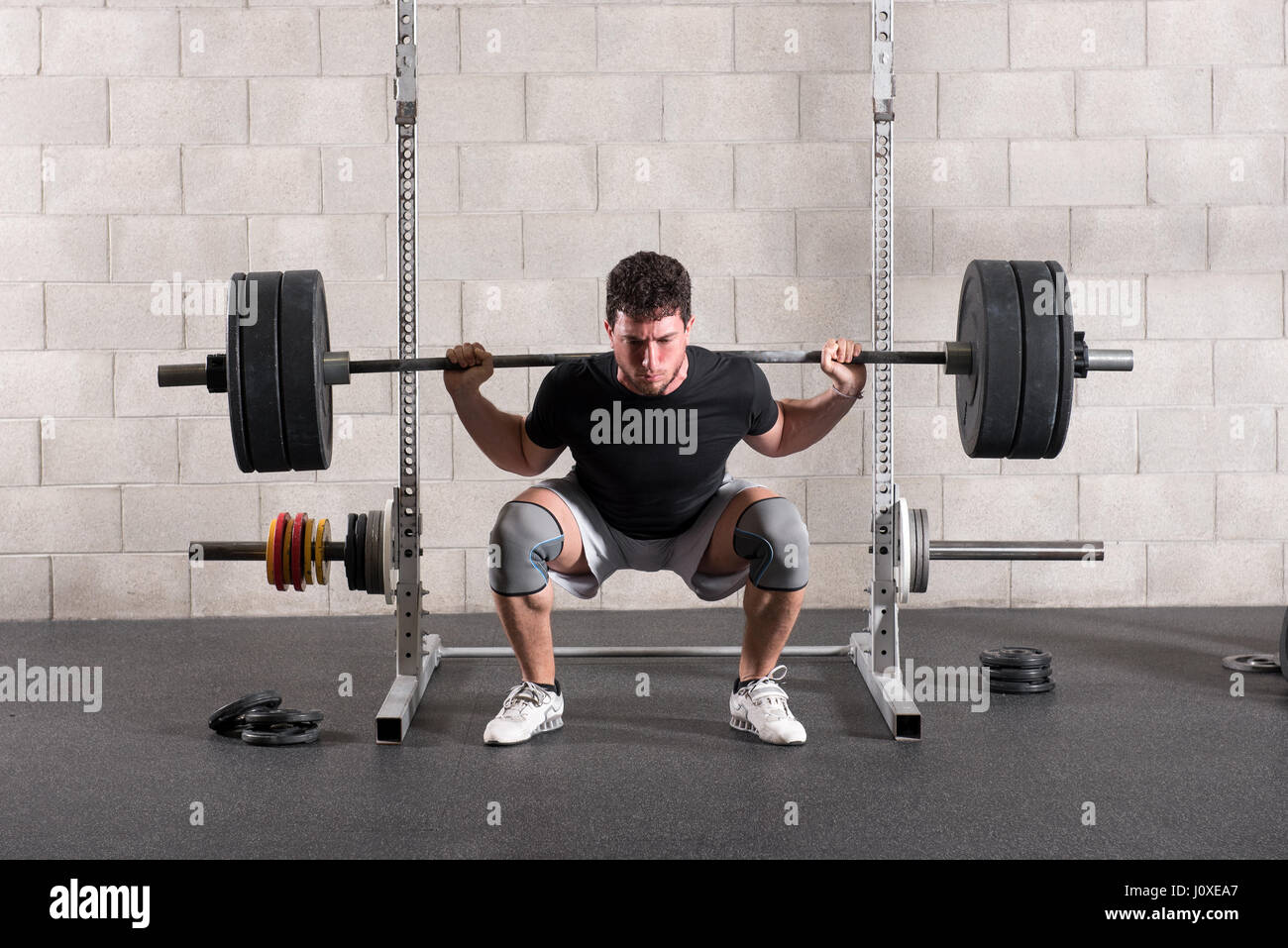 L'uomo facendo un crossfit back squat esercizio sollevando un barbell peso  sulle spalle mentre squatting prima in posizione eretta Foto stock - Alamy